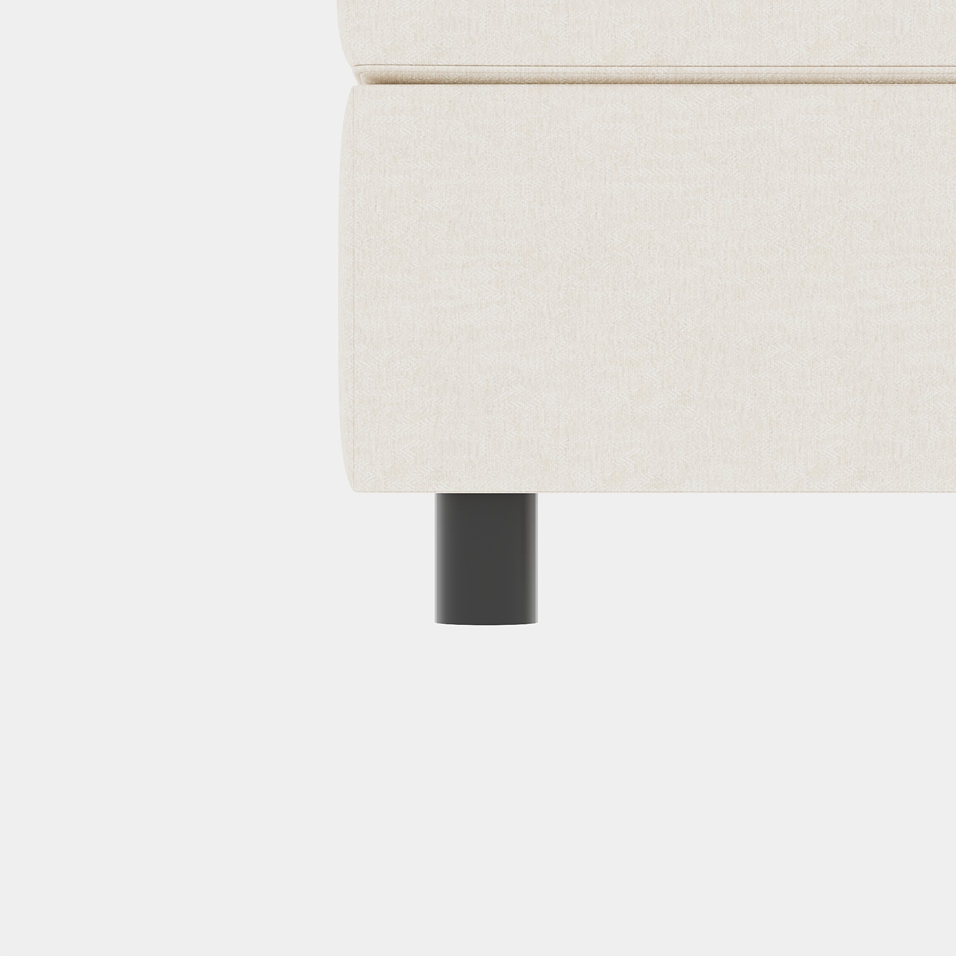 Closeup of a beige linen couch arm with a dark grey cylindrical leg