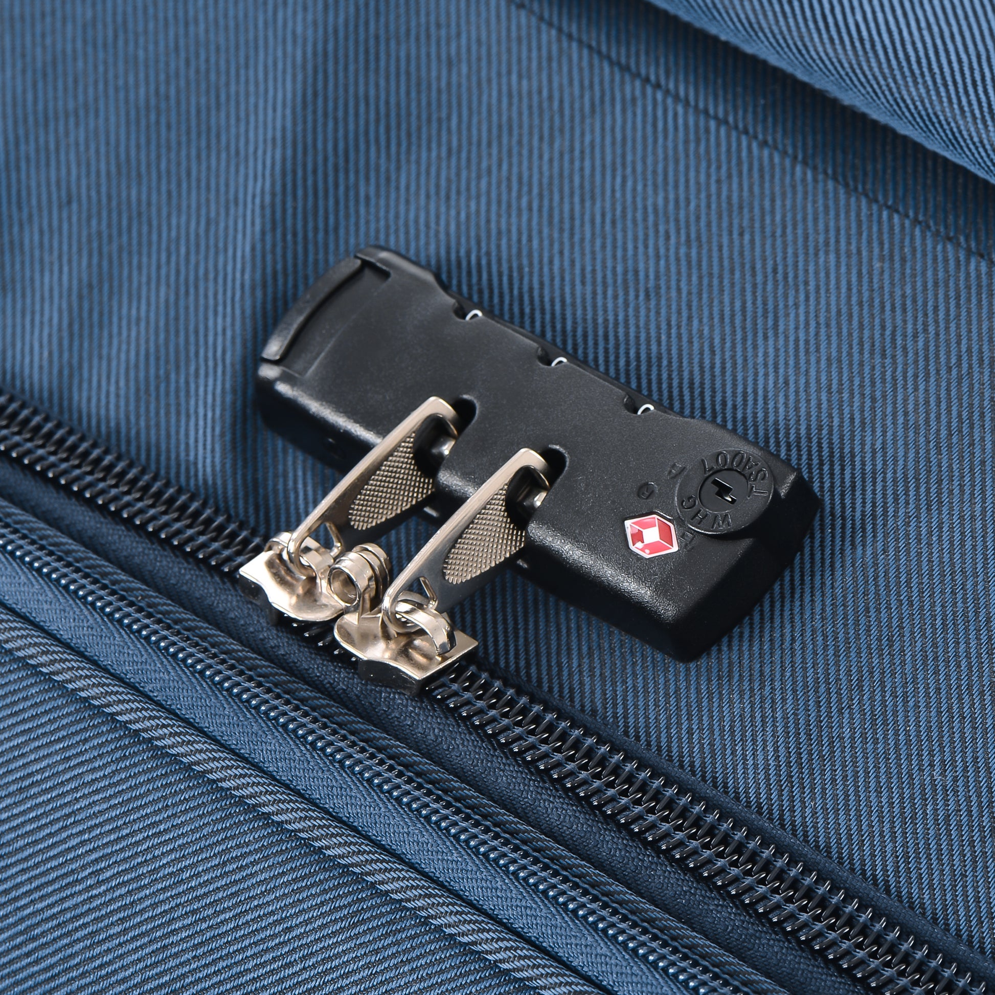 Blue fabric suitcase detail with black TSA combination lock and zippers