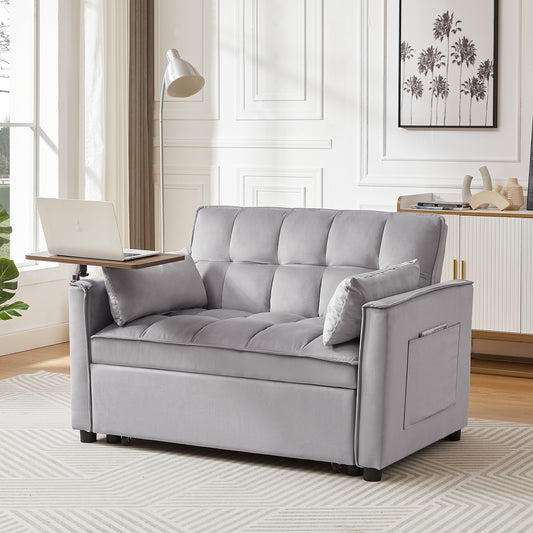 Gray velvet convertible sofa bed with a wooden tray table and laptop