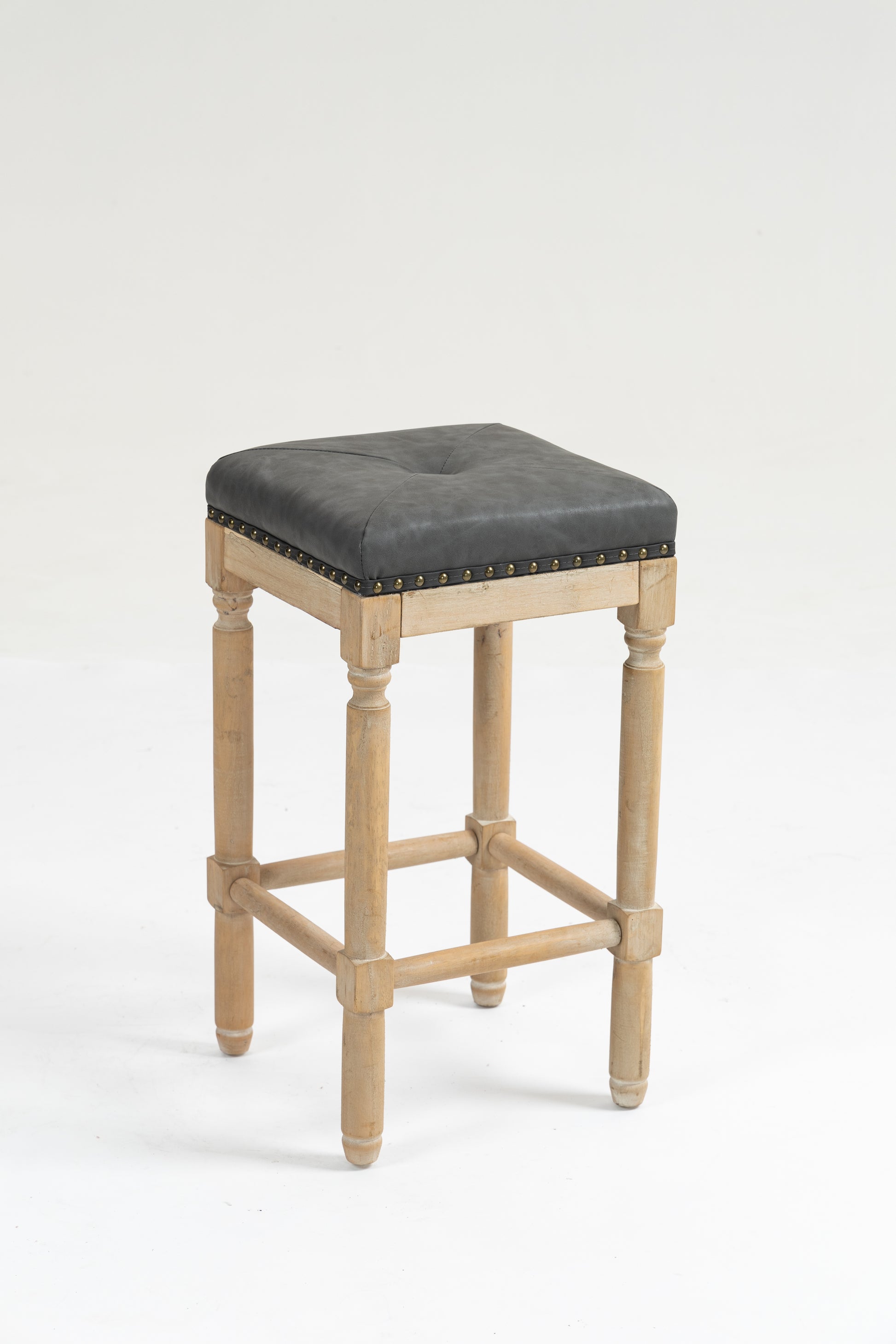 Distressed wood bar stool with square tufted grey faux leather seat and brass nailhead trim
