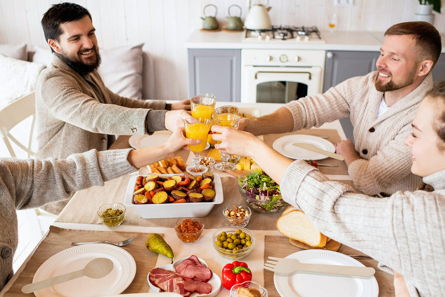 Four friends clinking glasses of orange juice at a homecooked meal