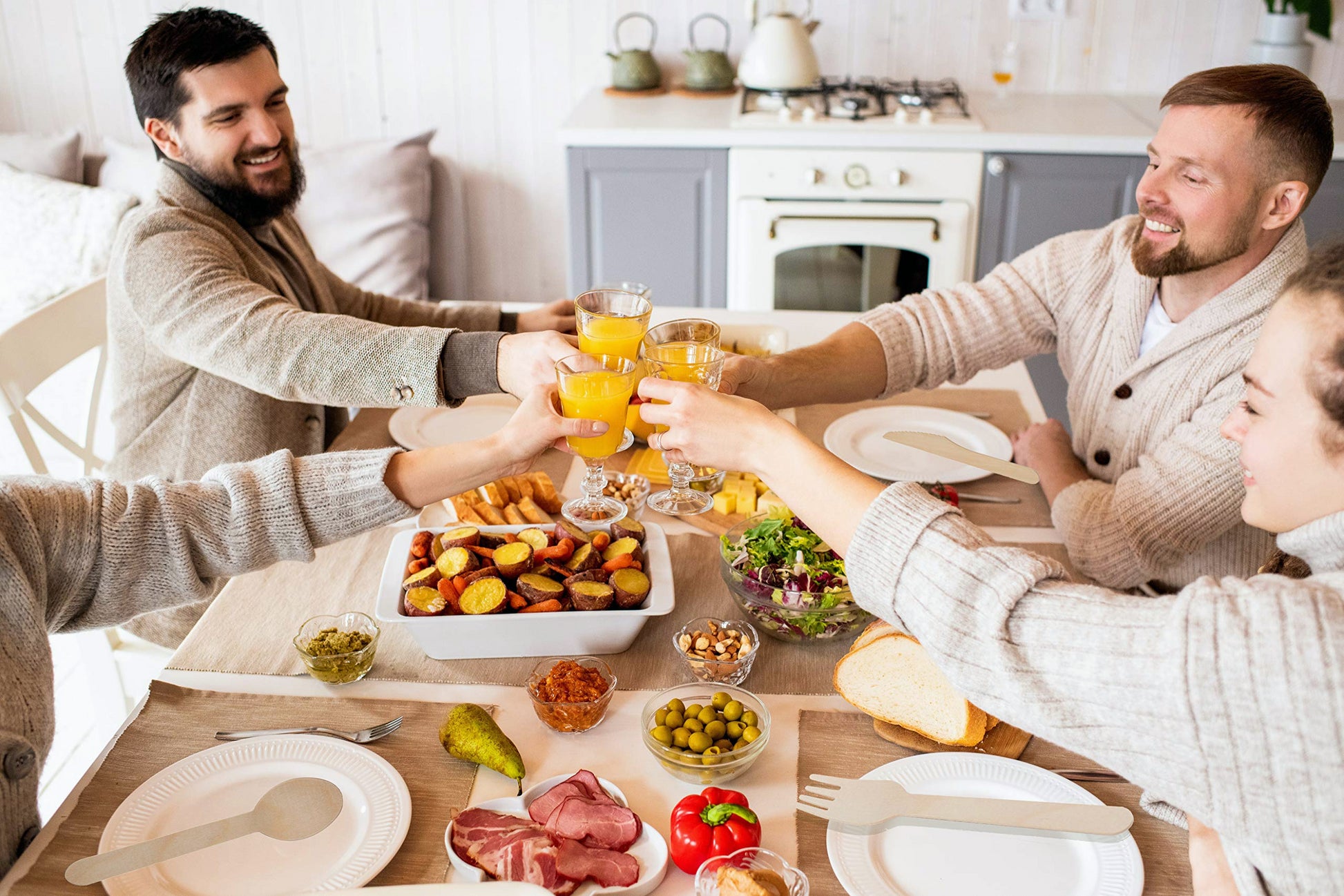 Four friends clinking glasses of orange juice at a homecooked meal