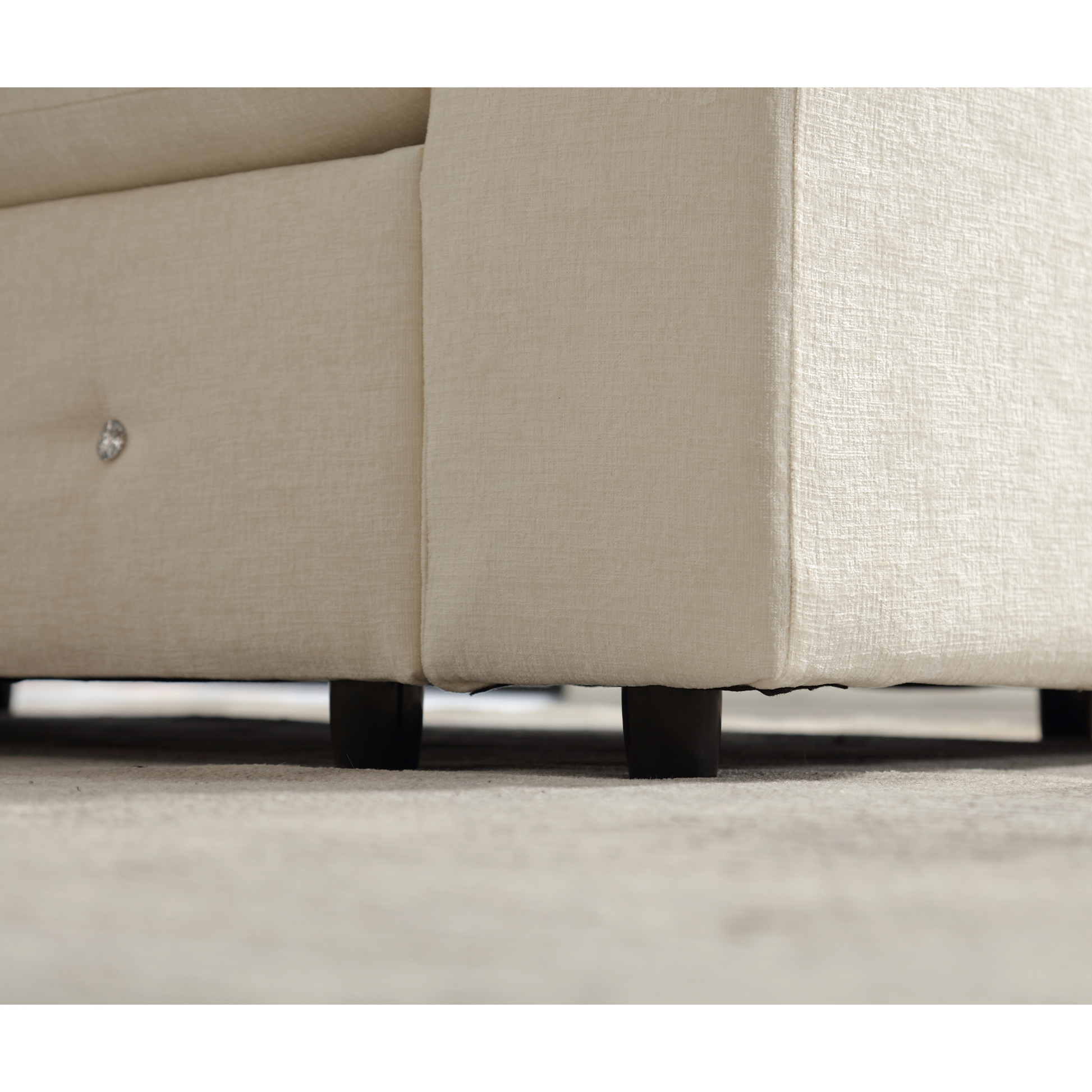 Closeup of a cream upholstered couch armrest with tufted detail