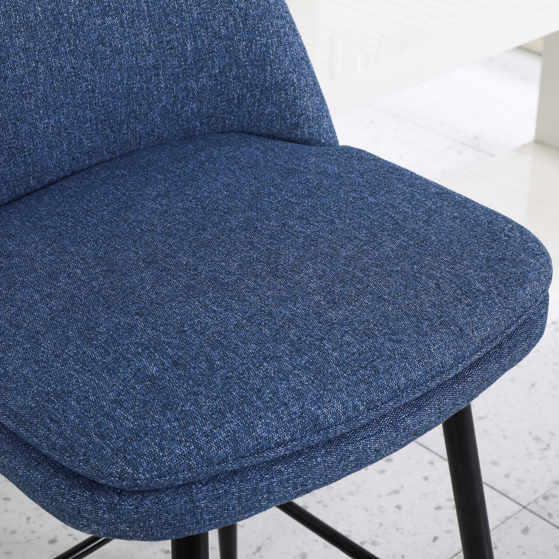 Textured blue upholstered seat and back of a modern dining chair with black legs