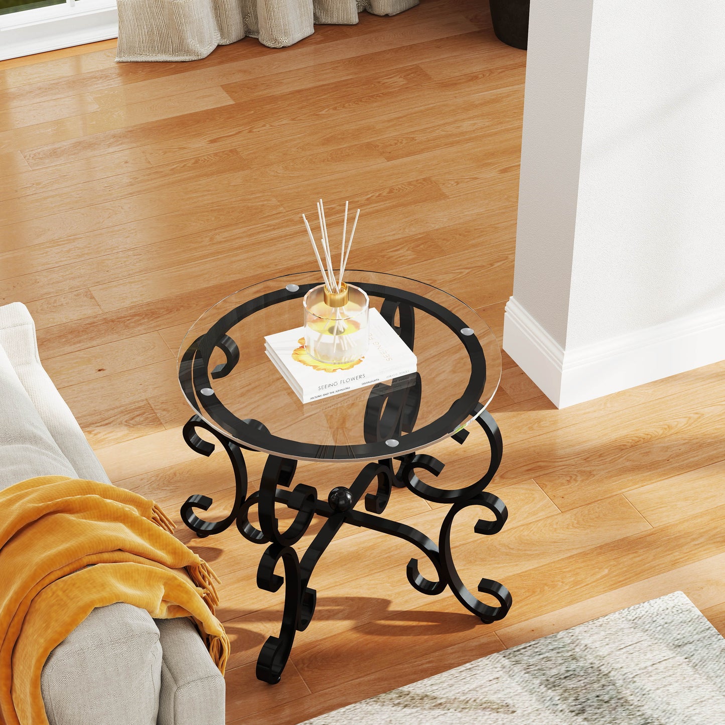 Round glass top coffee table with ornate black metal base and decorative scrollwork