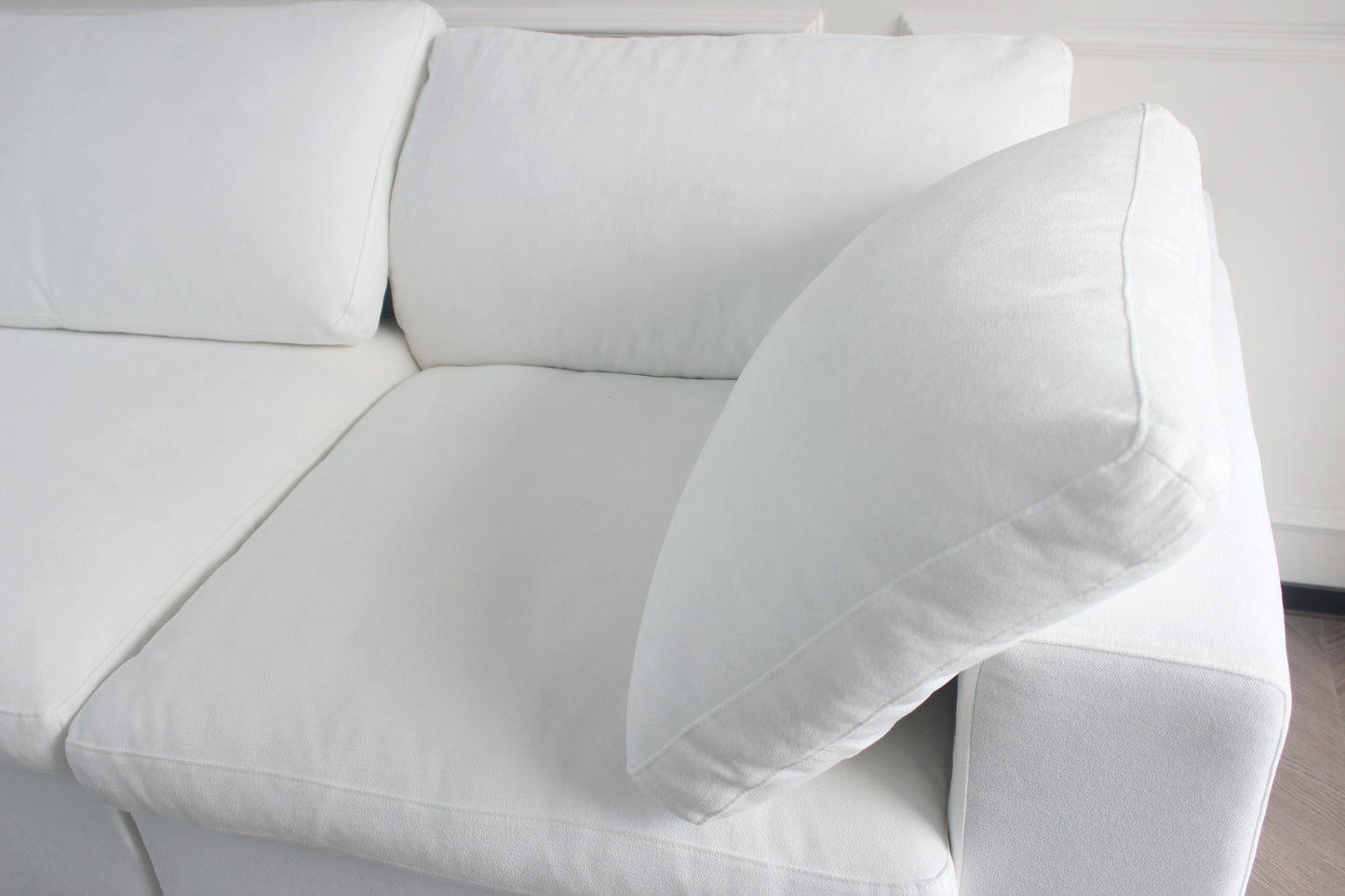 Plush white linen sofa with deep seat cushions and a soft lumbar pillow