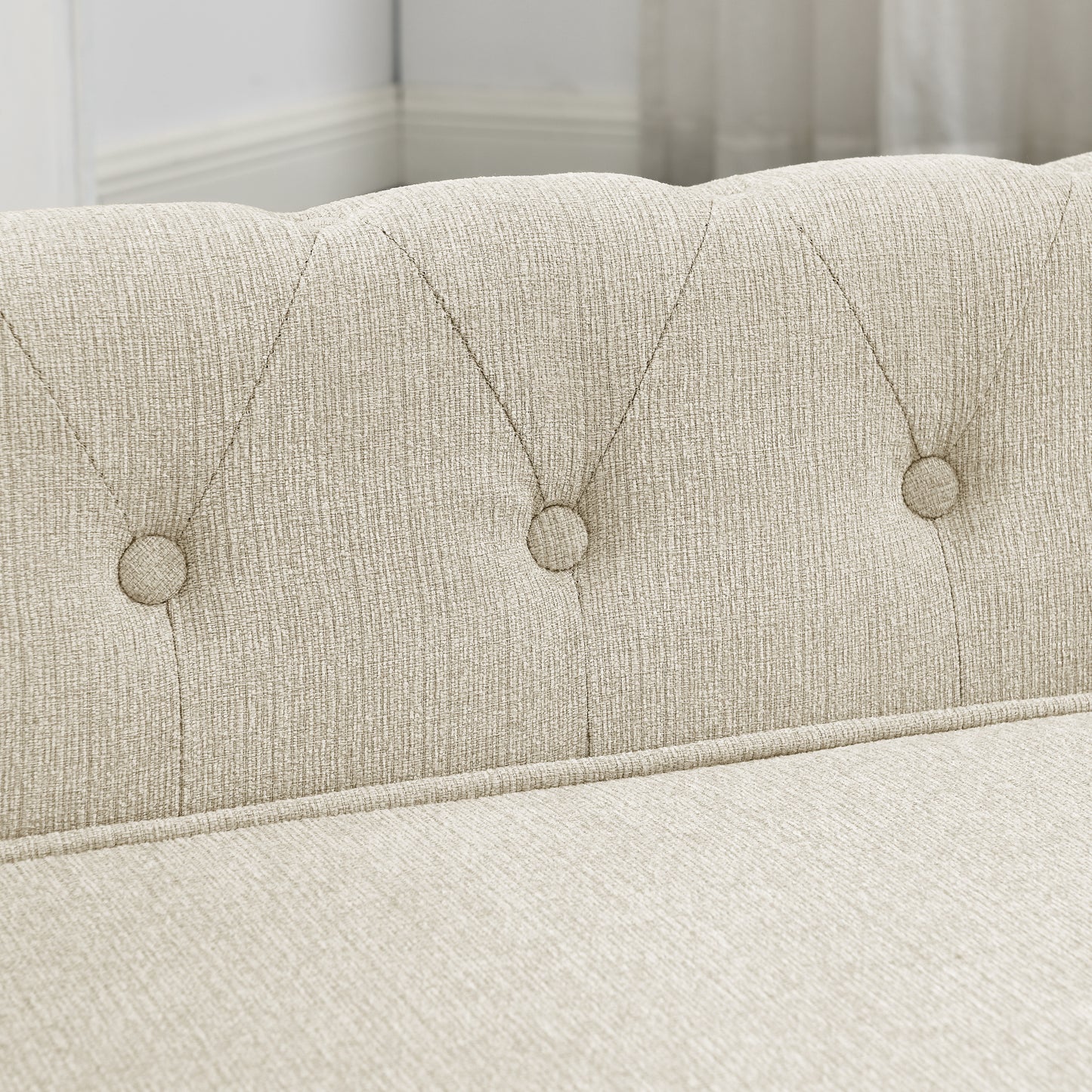 Closeup of beige linen upholstered sofa with button tufting on the backrest