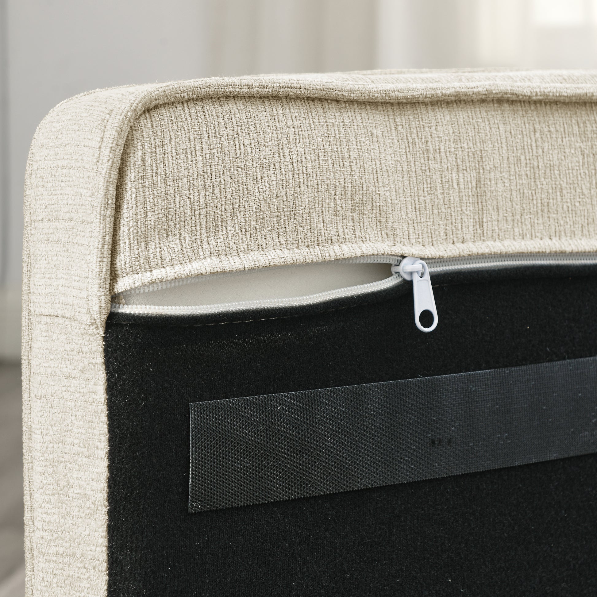 Close up of beige textured upholstery fabric with a white zipper closure on a sofa component