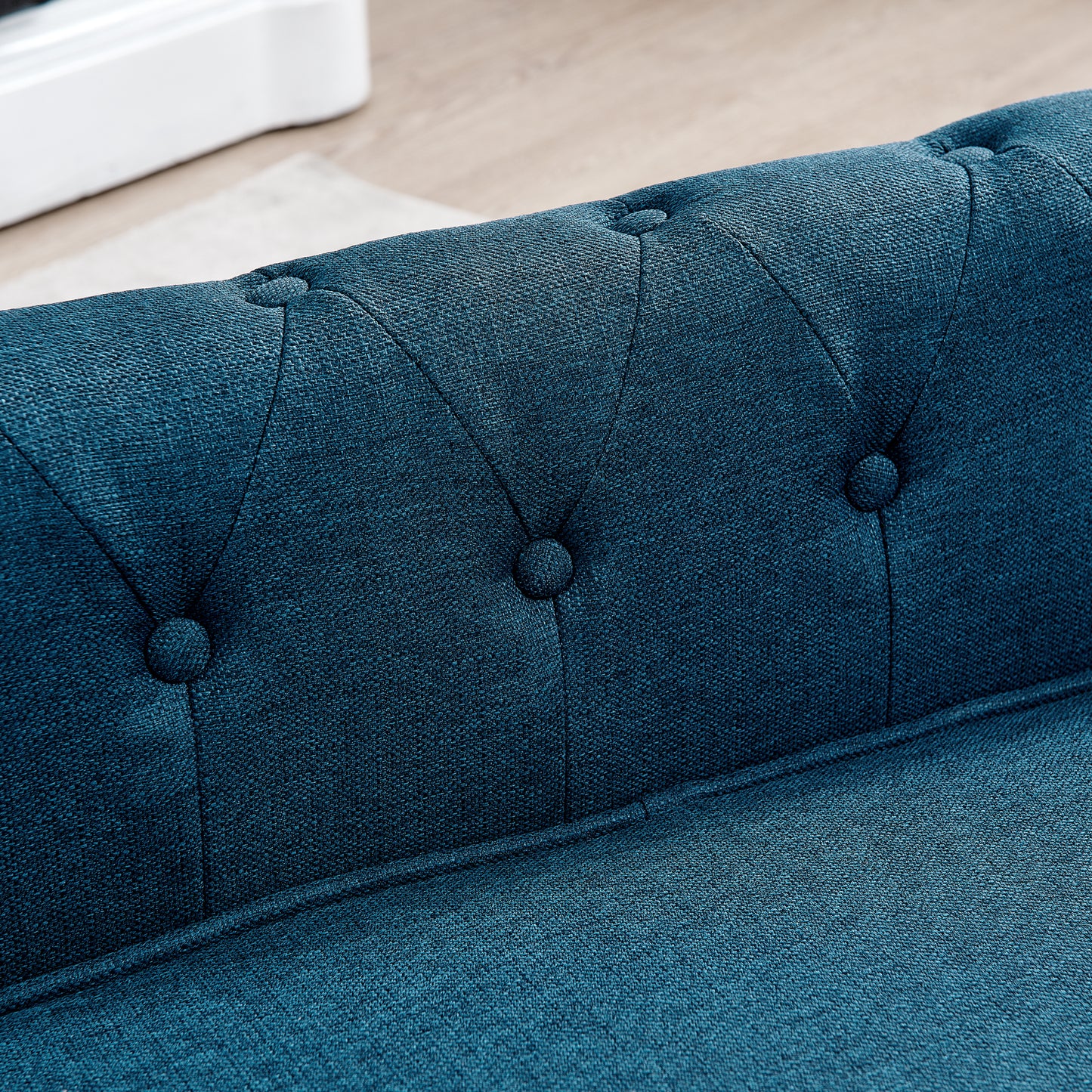 Tufted deep teal blue fabric sofa detail showing button accents and textured upholstery
