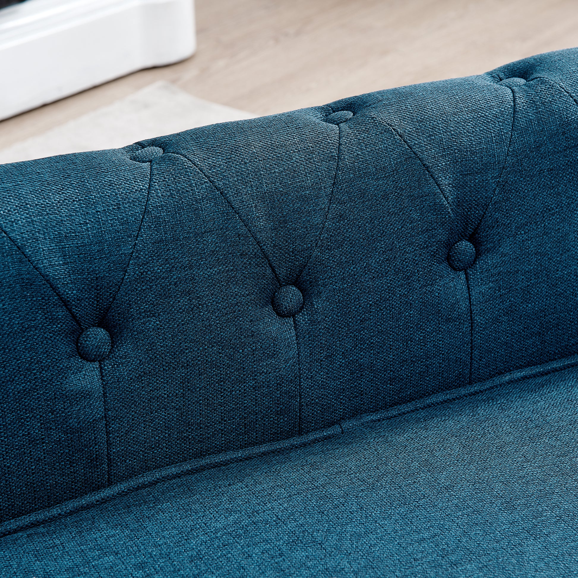 Tufted deep teal blue fabric sofa detail showing button accents and textured upholstery