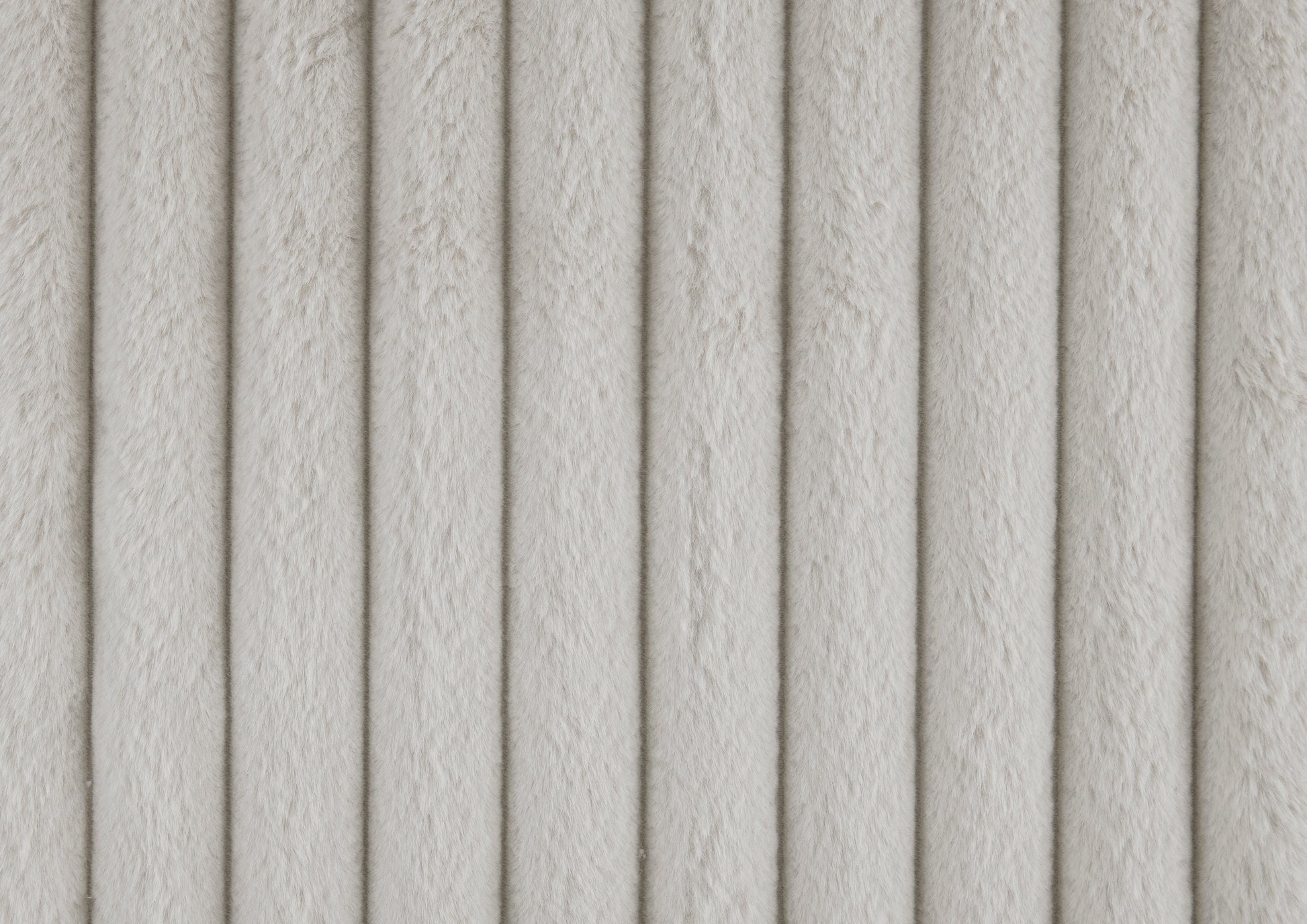 Plush faux fur fabric in a light cream color with vertical ribbing perfect for cozy upholstery