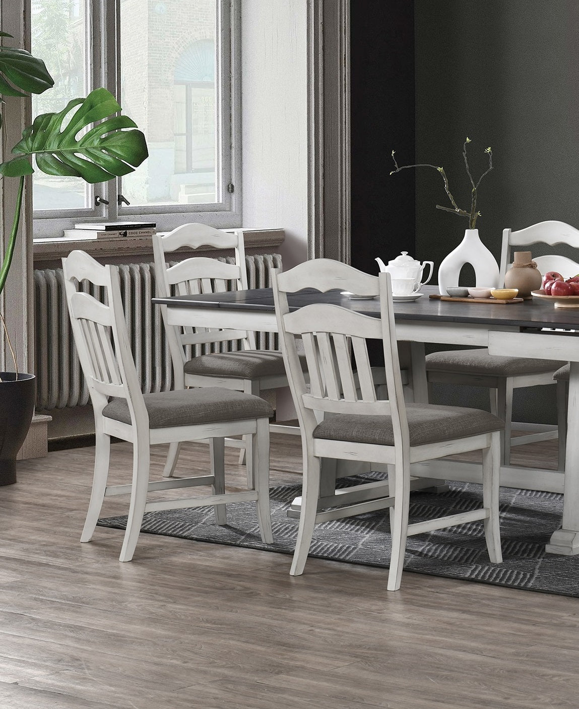 Four distressed white dining chairs with grey upholstered seats around a dark wood table