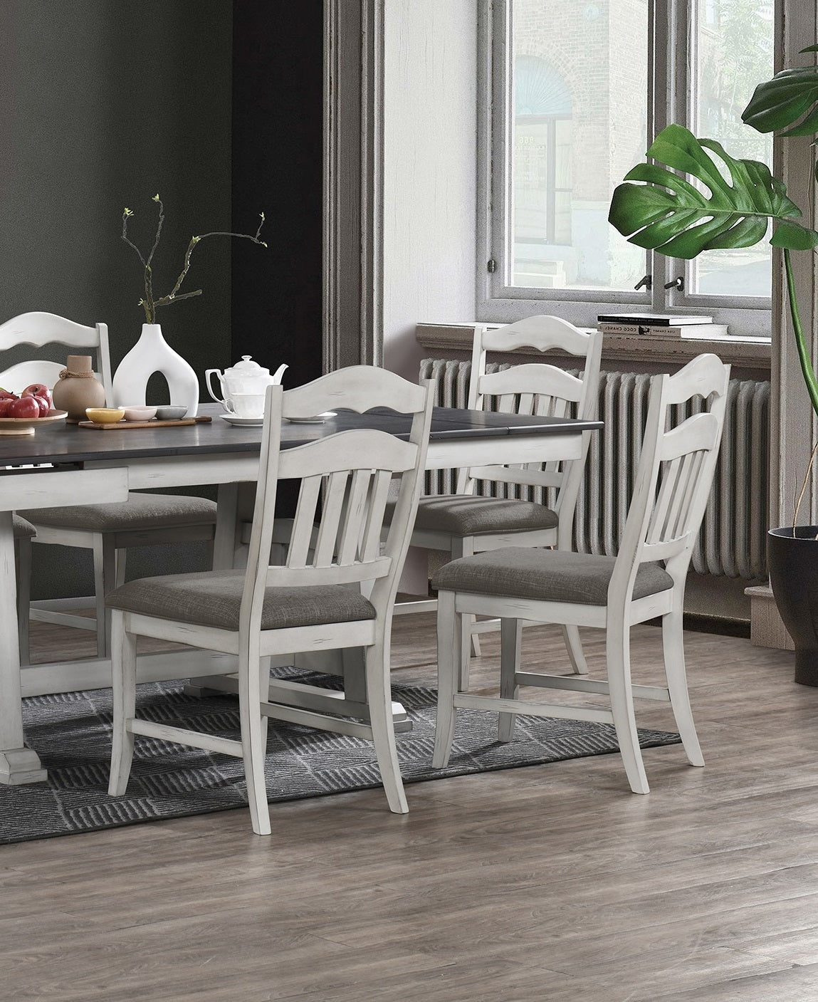 Distressed white dining chairs with upholstered grey seats around a dark wood table