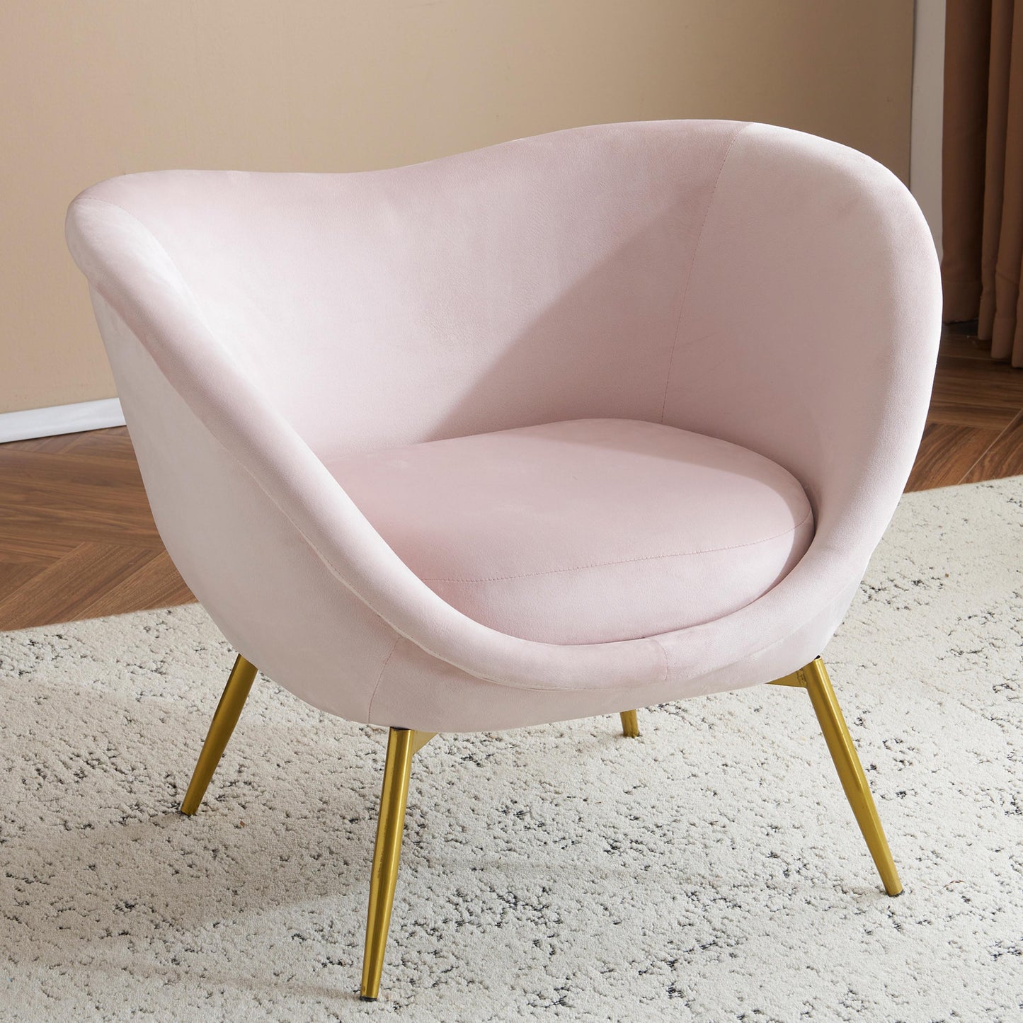 Blush pink velvet accent chair with comfortable curved seat and gold tapered legs