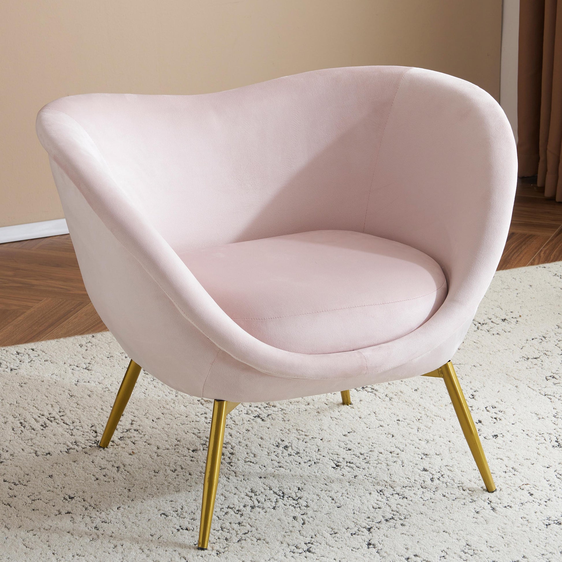 Blush pink velvet accent chair with comfortable curved seat and gold tapered legs