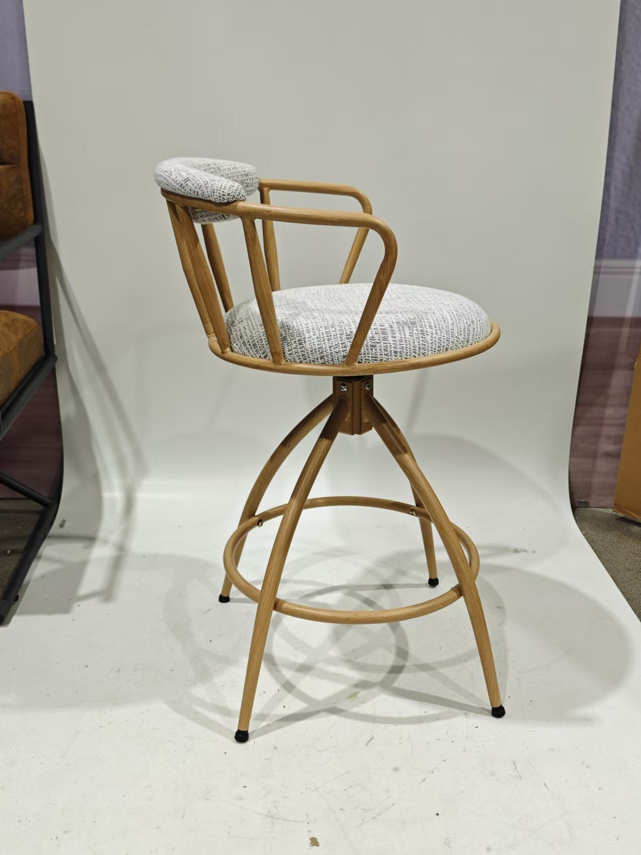 Swiveling wooden bar stool with light grey patterned fabric seat and backrest