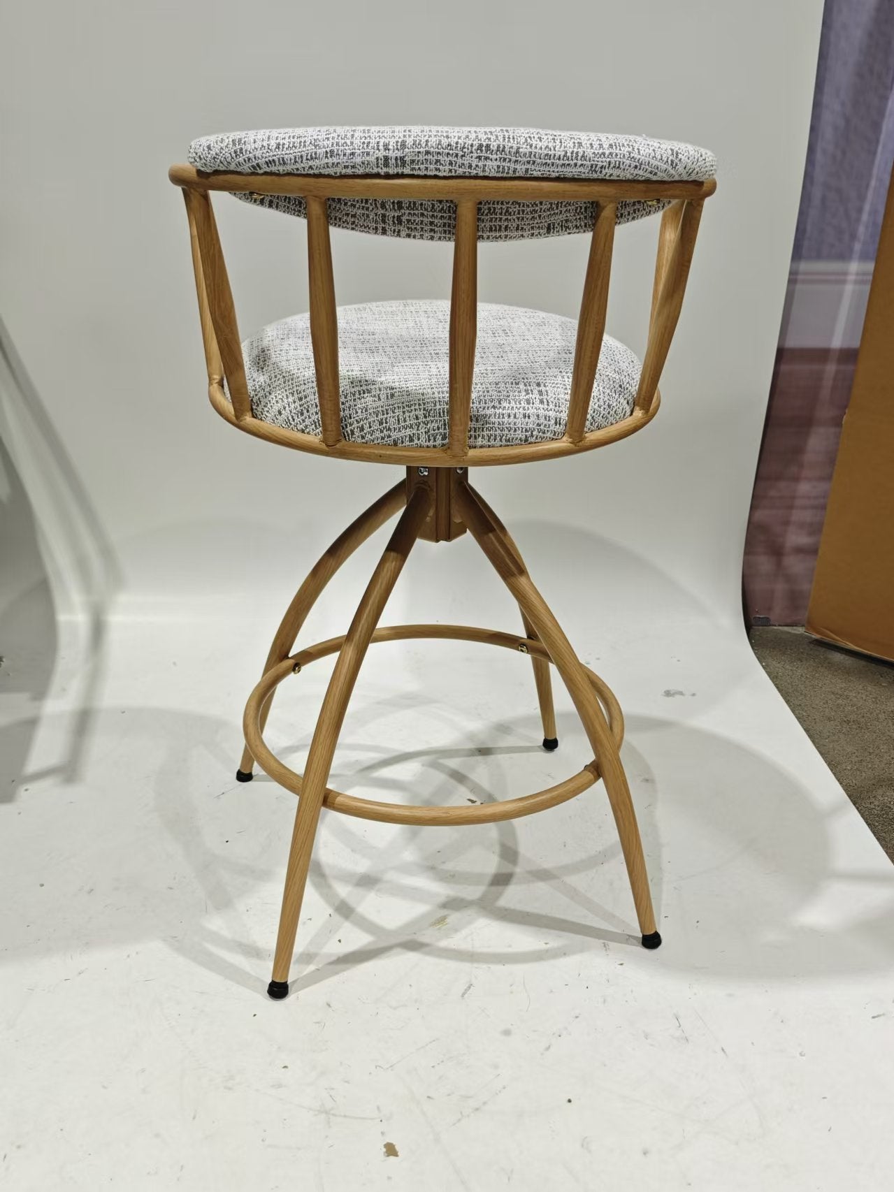 Swivel bar stool with light wood frame and grey textured upholstered seat and backrest