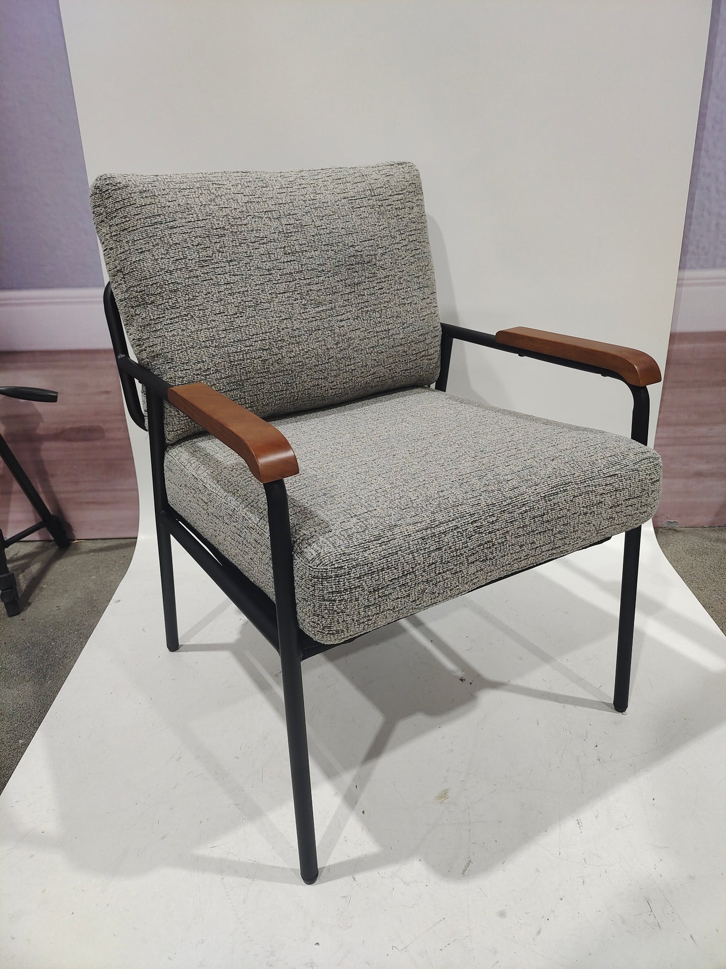 Textured grey fabric accent chair with black metal frame and wood armrests