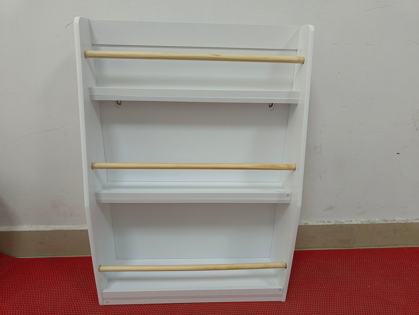 White wooden childrens bookshelf with three shelves and wooden dowels for books