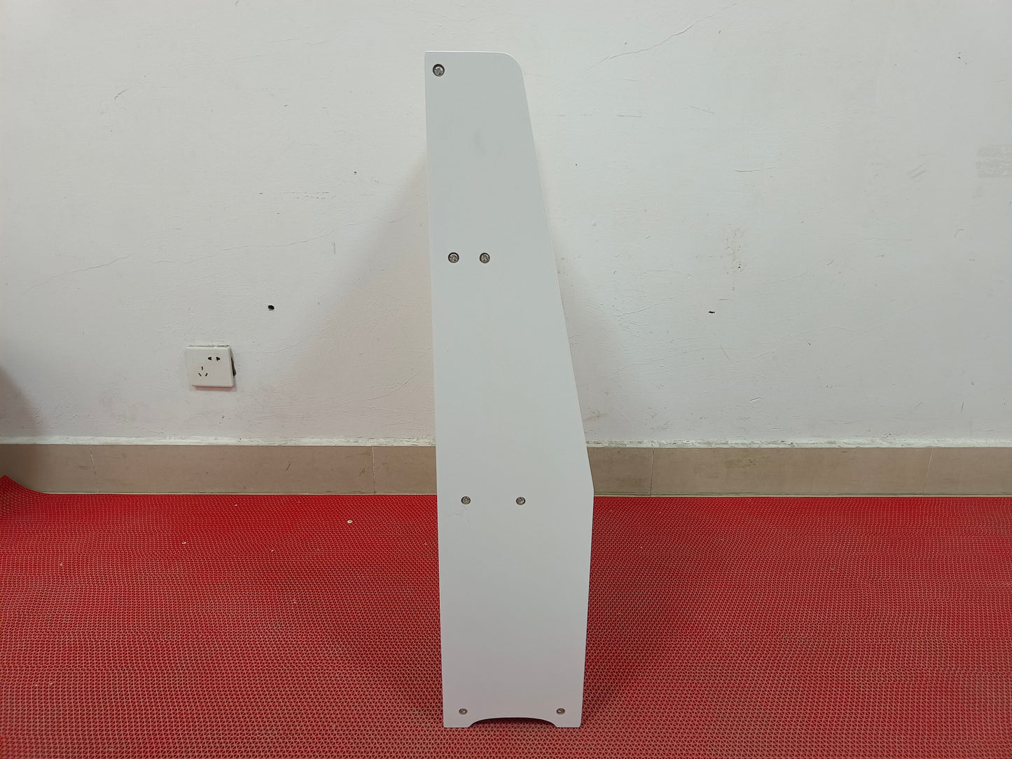 White particle board shelf edge with visible screw fasteners and curved bottom detail