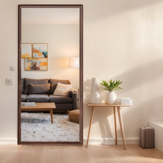 Tall floor mirror with a dark wood frame reflecting a modern living room interior