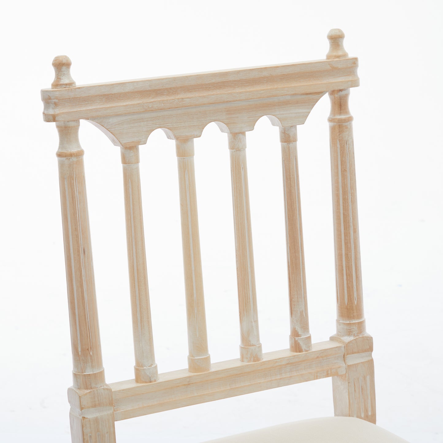Distressed white wooden chair back with turned spindles and decorative top