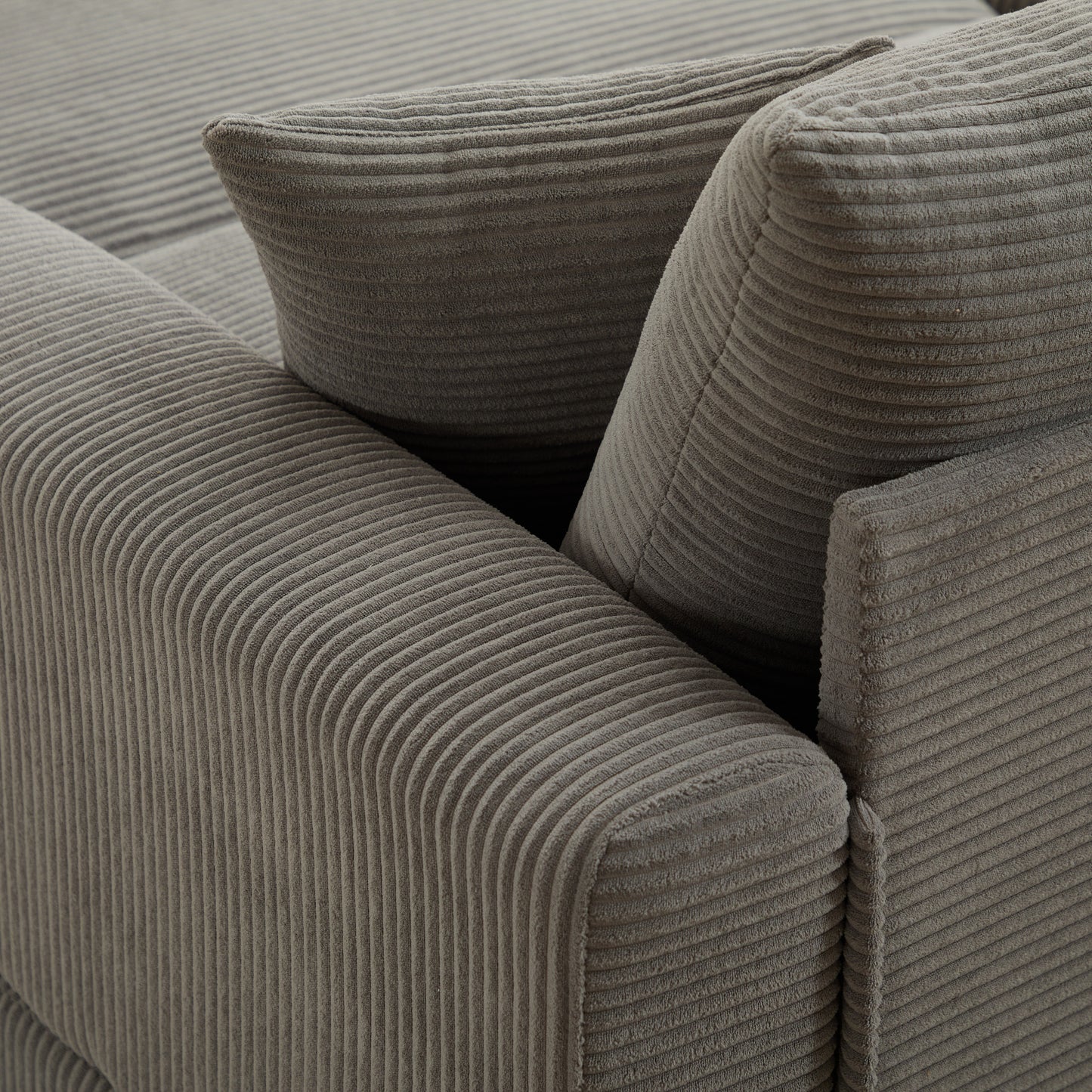 Closeup of a grey corduroy sofa armrest with textured fabric detail