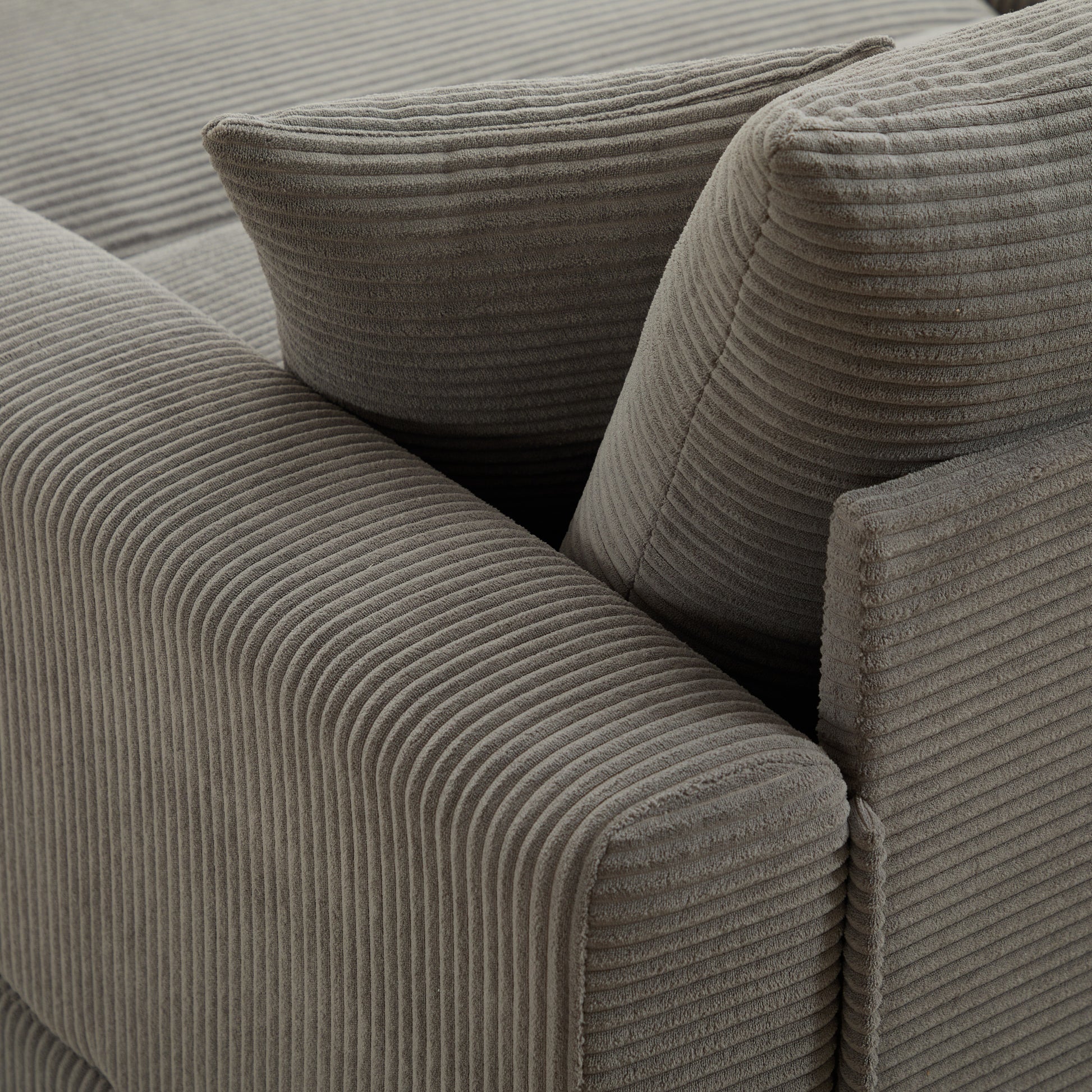 Closeup of a grey corduroy sofa armrest with textured fabric detail