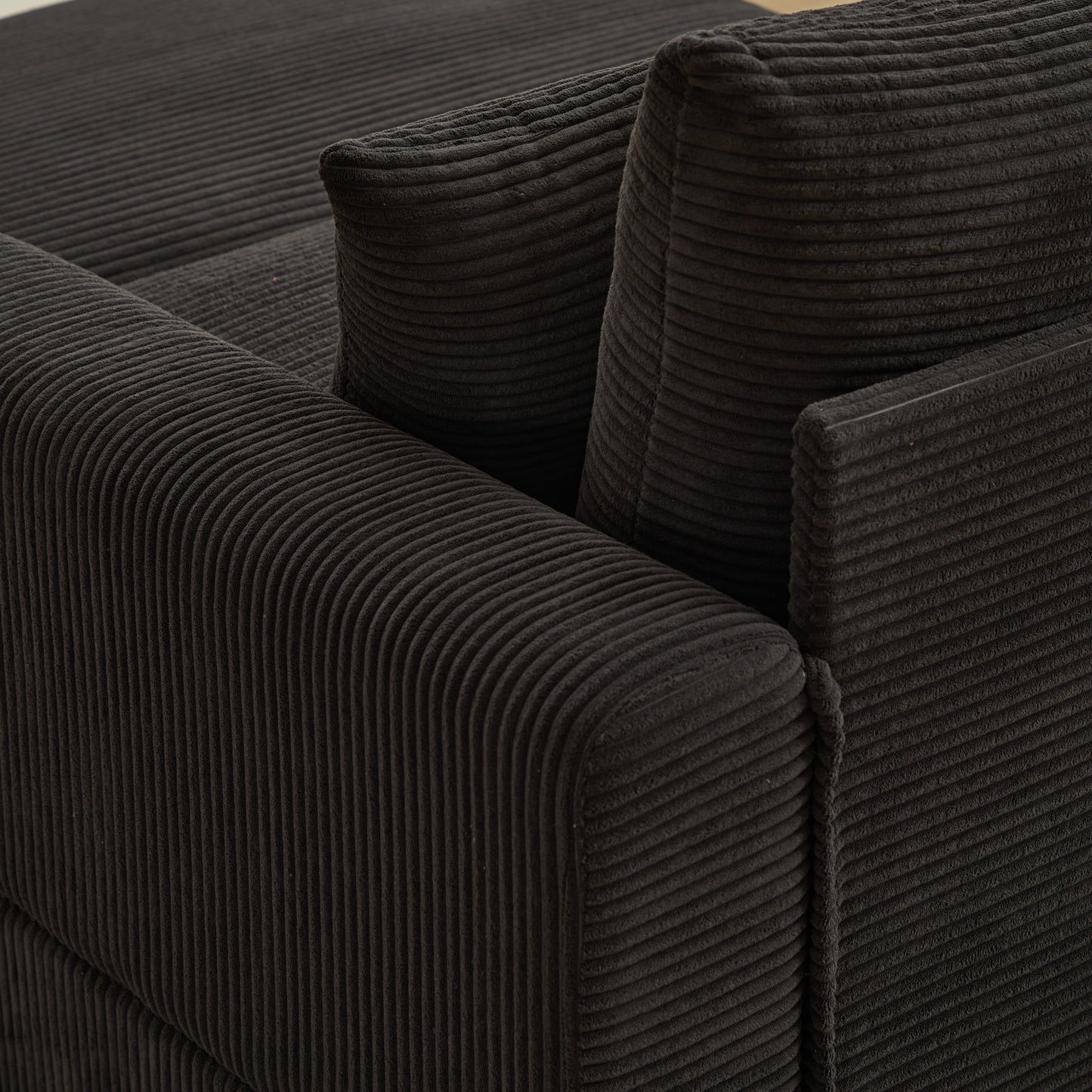 Closeup of a charcoal grey corduroy sofa armrest with plush cushioning