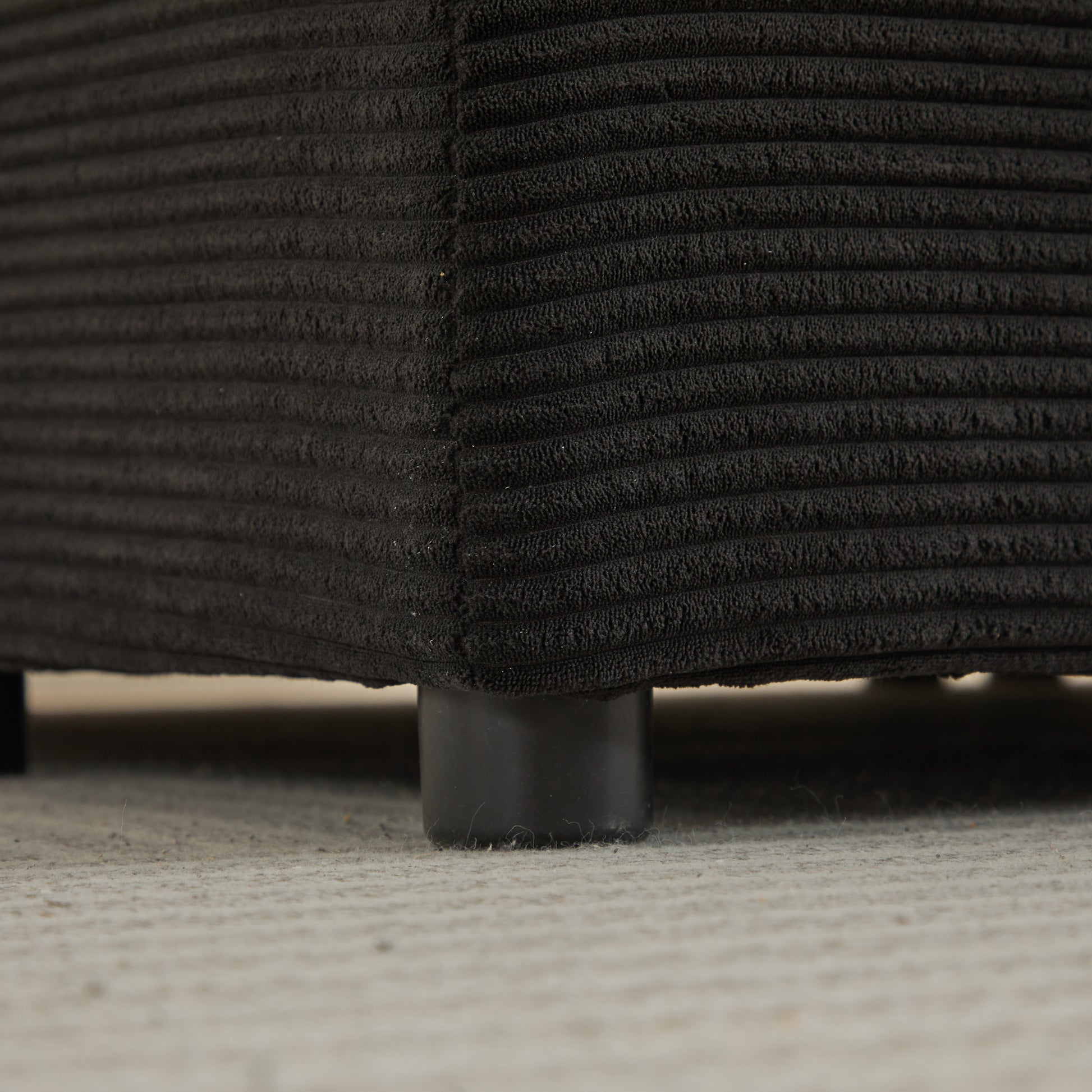 Closeup of dark grey corduroy fabric on a sofa cushion with textured ribs