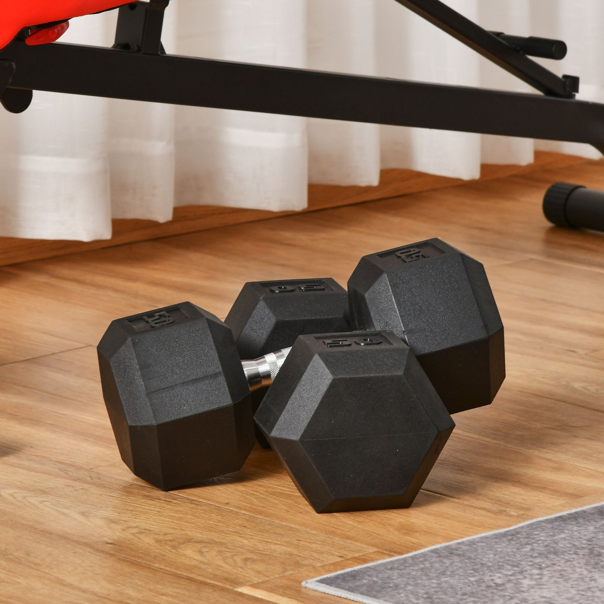 Pair of black hexagonal dumbbells with lb weight markings resting on wood floor