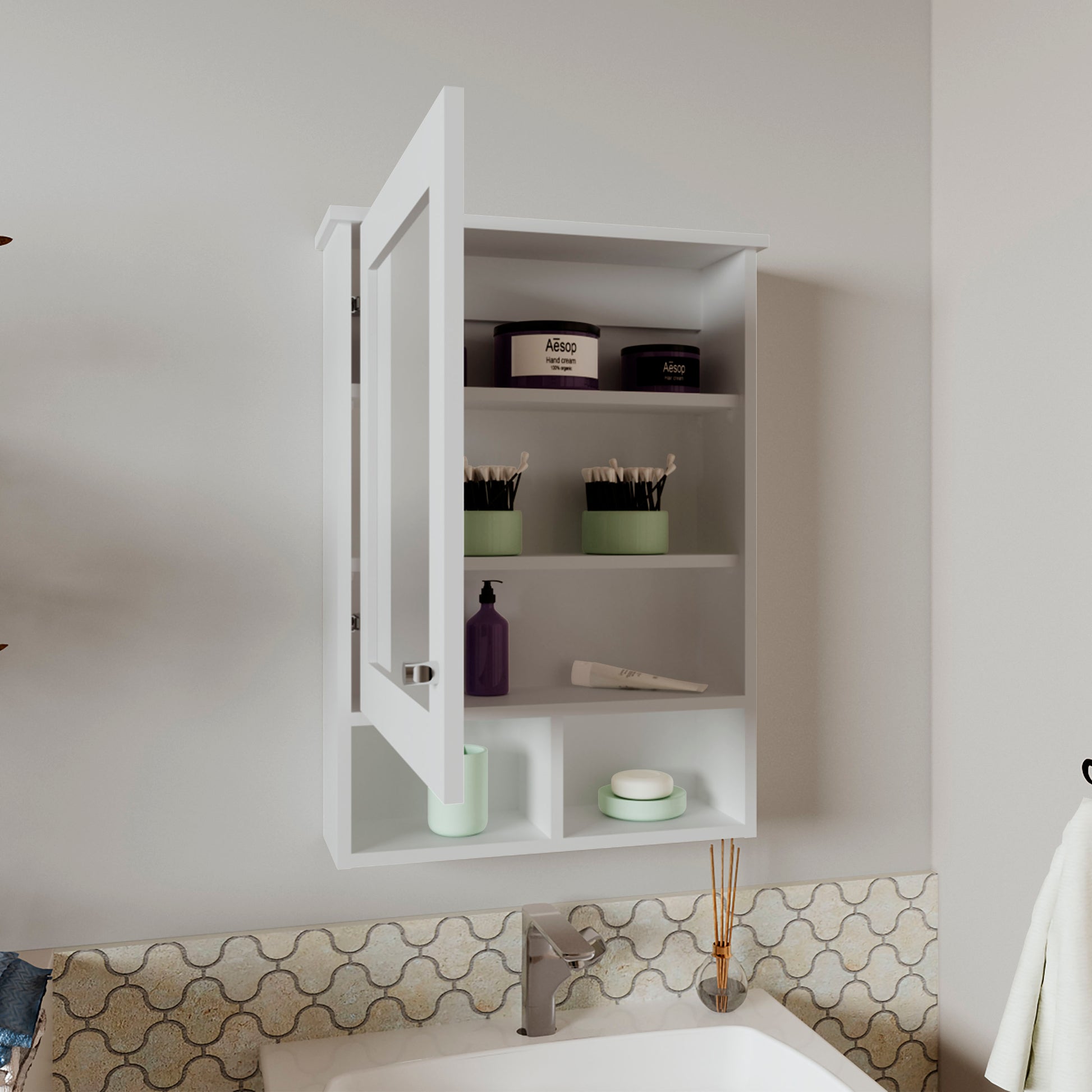 White medicine cabinet with open door displaying Aesop hand cream and makeup brushes