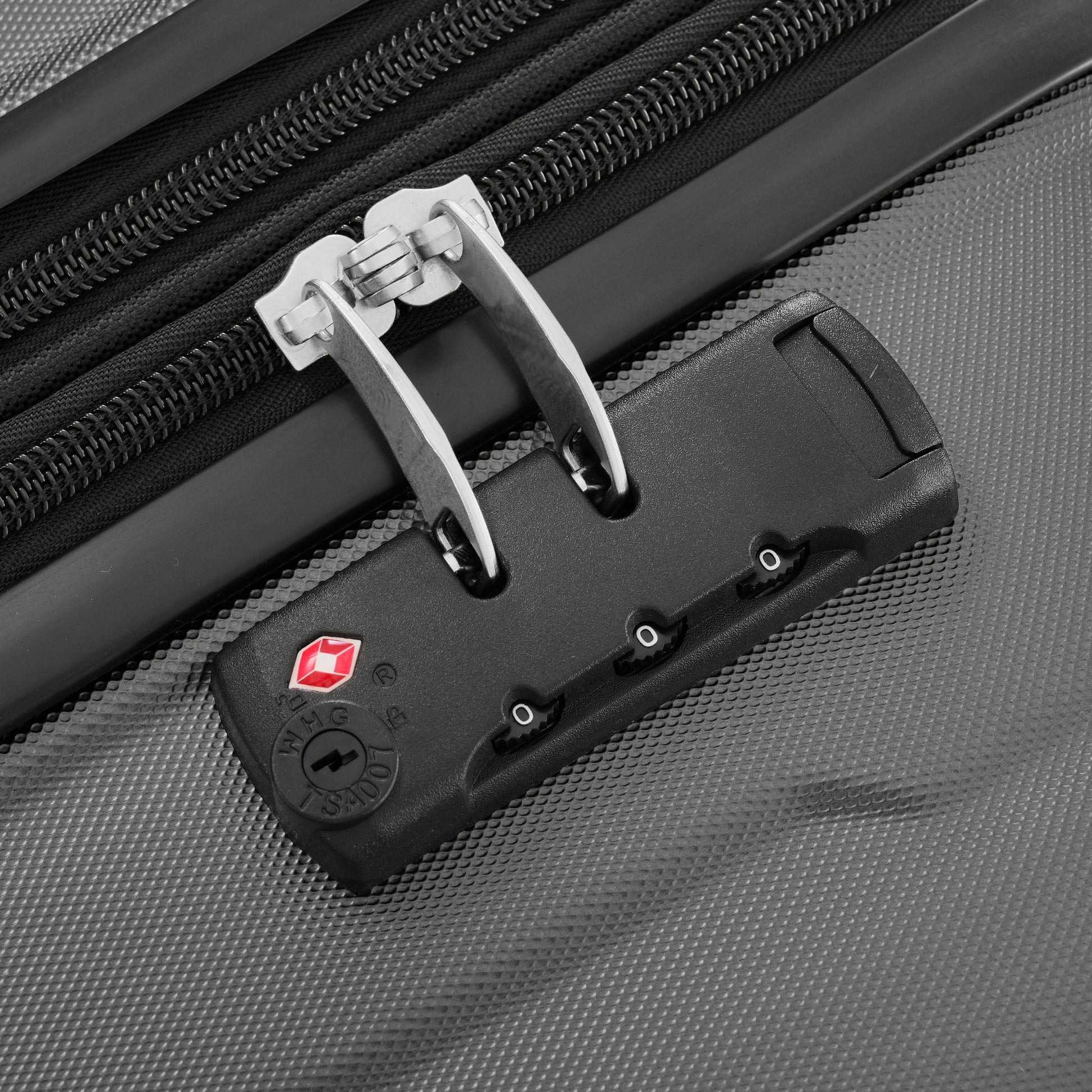 Closeup of a TSA lock with silver clasps on a textured grey suitcase ideal for travel