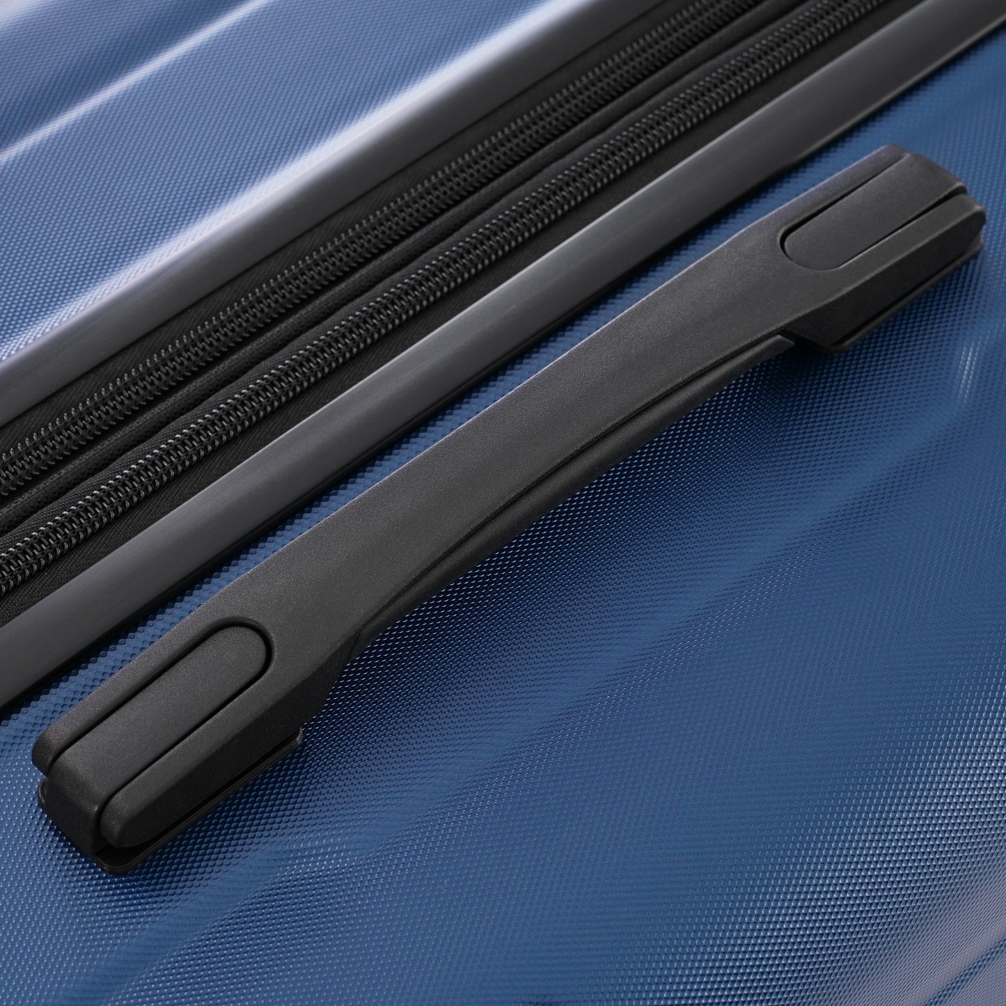 Closeup of a navy blue textured hardside suitcase with a black retractable handle and zipper track