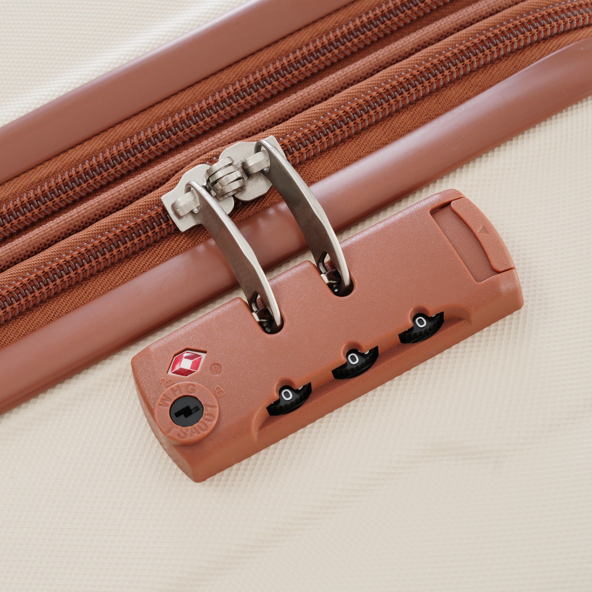 Brown TSA luggage lock with integrated zipper on a lightcolored suitcase