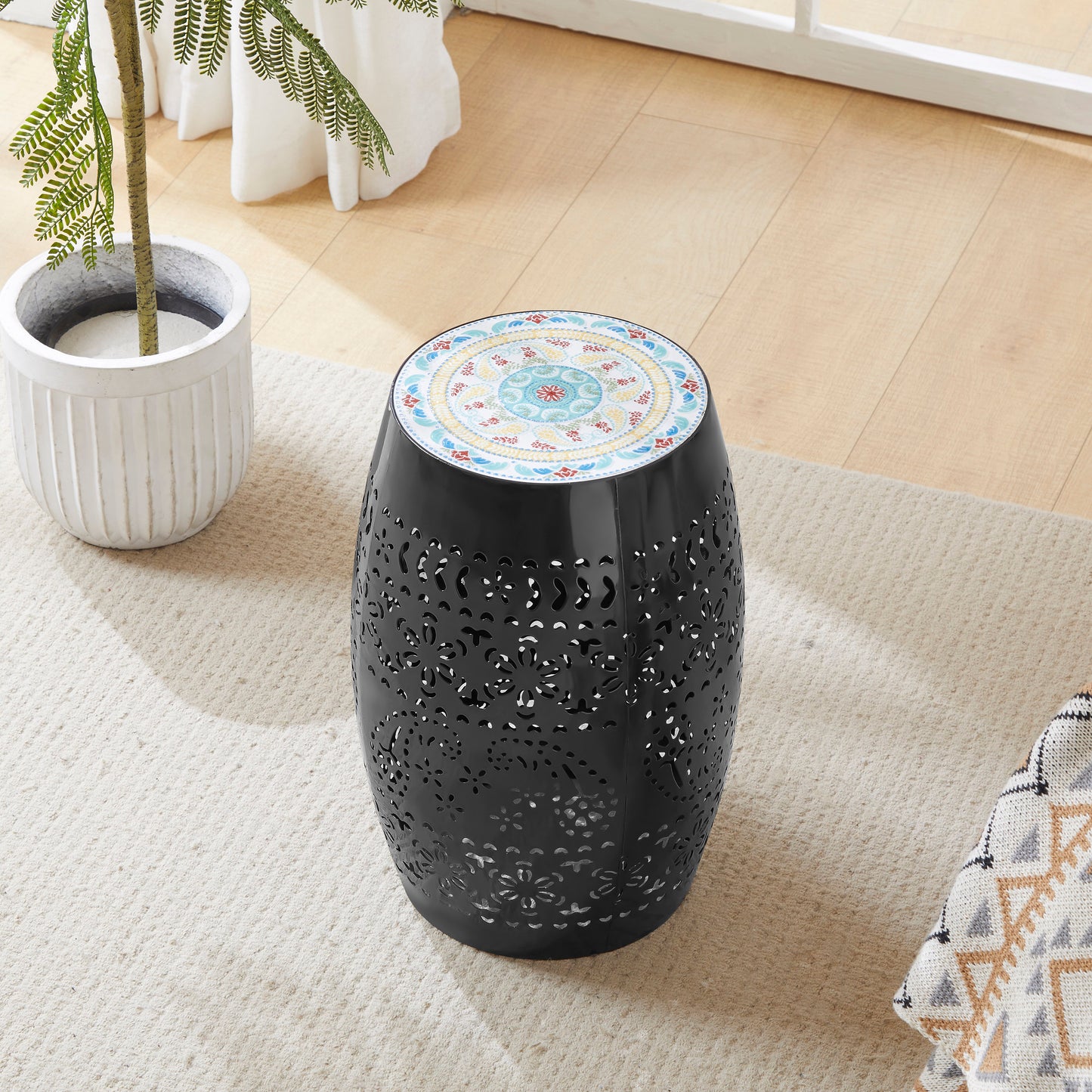 Black metal garden stool with intricately cut floral patterns and a mosaic tiled top