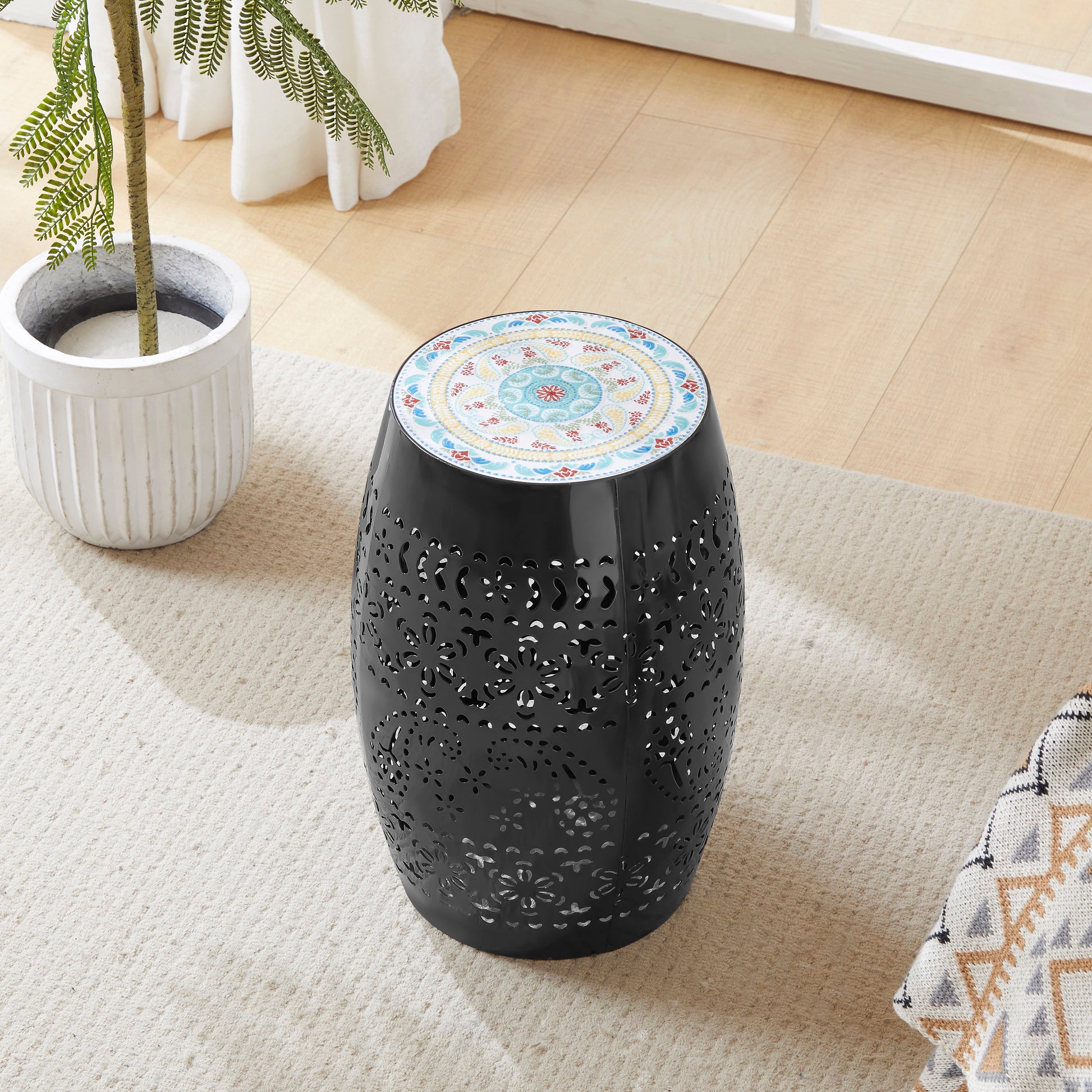 Black metal garden stool with intricately cut floral patterns and a mosaic tiled top
