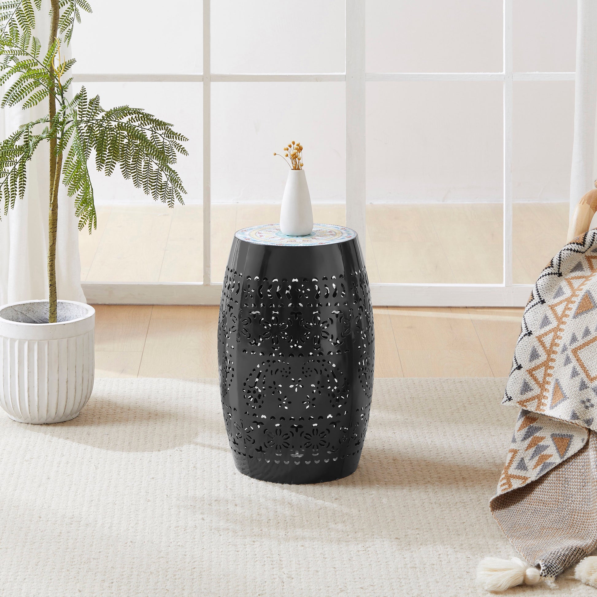 Black metal garden stool with intricate floral cutouts and a mosaic top