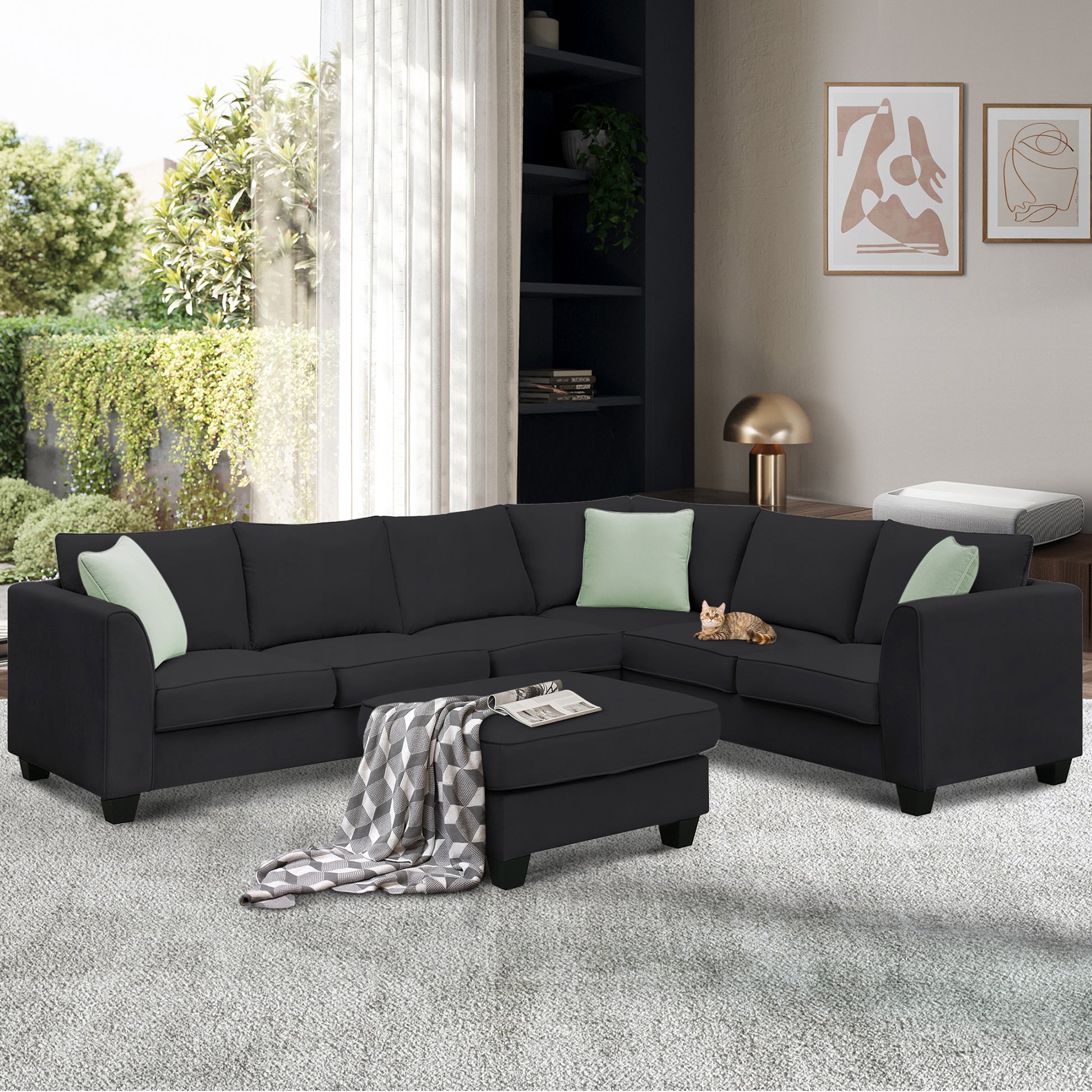Dark charcoal sectional sofa with ottoman and light green pillows in a modern living room