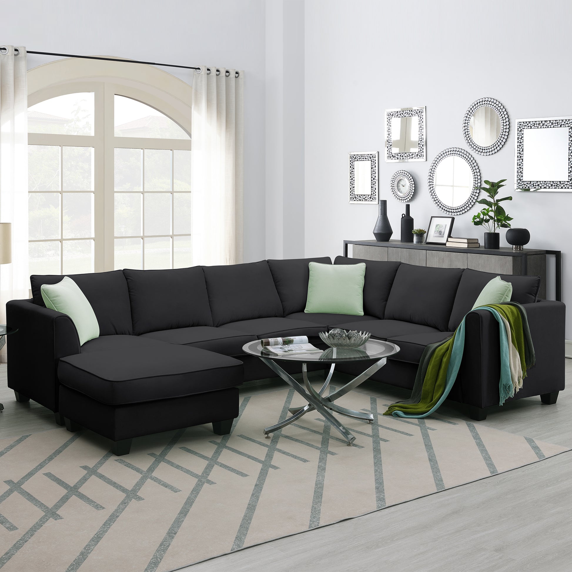 Black upholstered sectional sofa with chaise and light green accent pillows