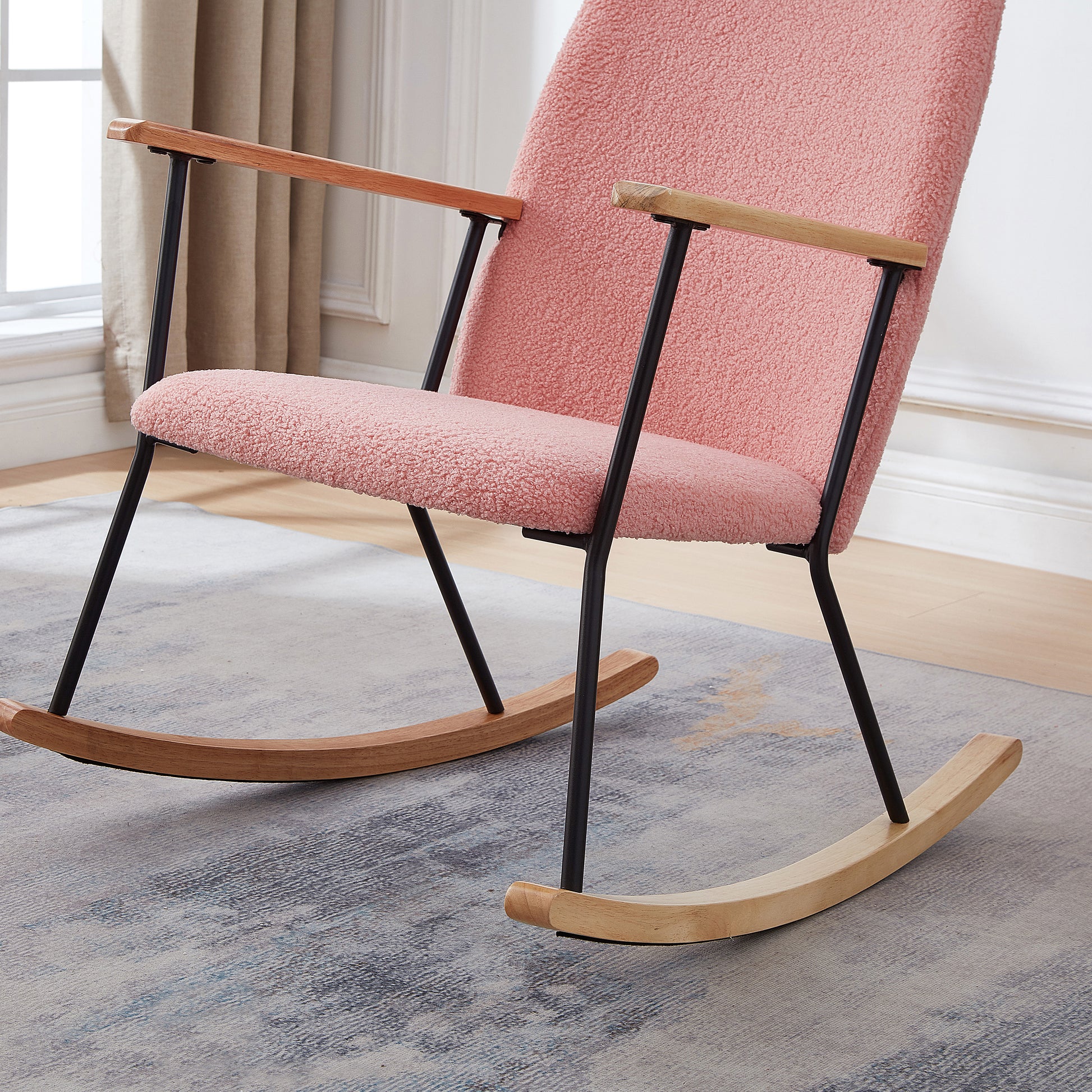 Pink boucle fabric rocking chair with natural wood arms and black metal frame