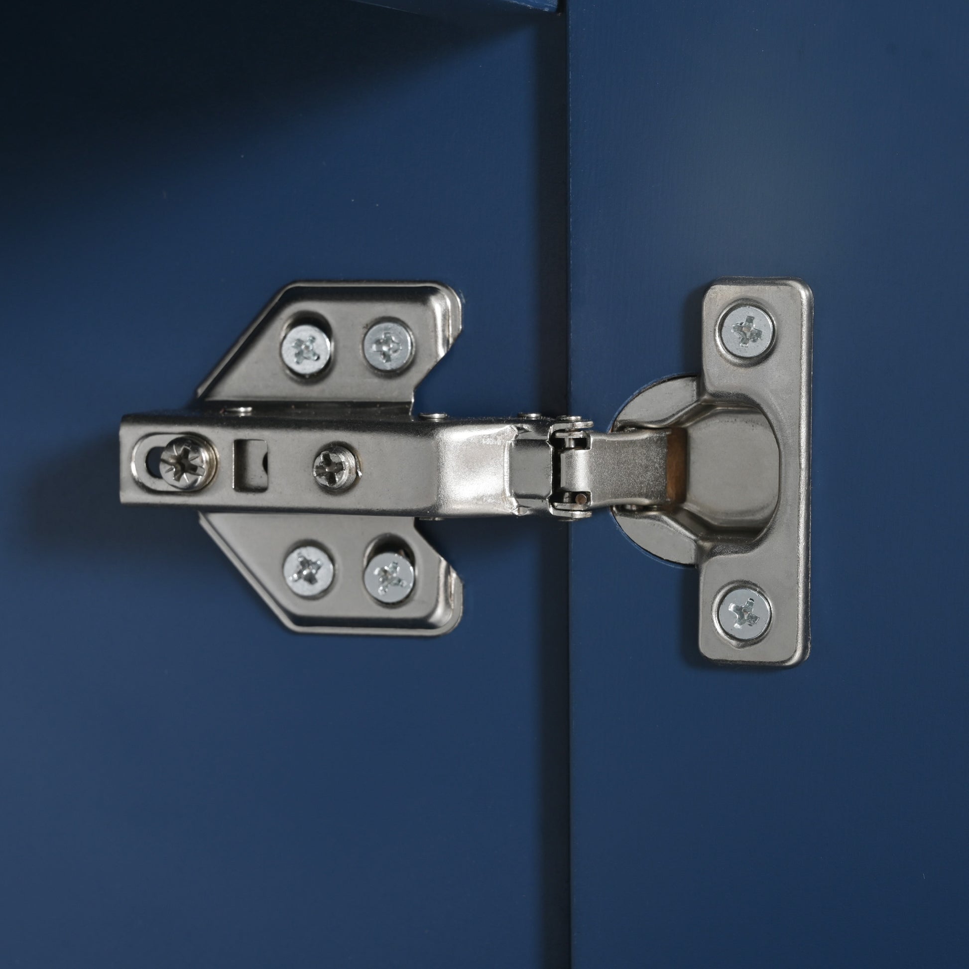 Brushed nickel cabinet hinge with screws on navy blue door