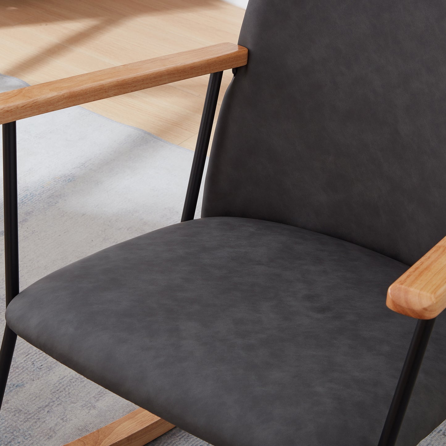 Dark gray upholstered accent chair with natural wood arms and black metal legs