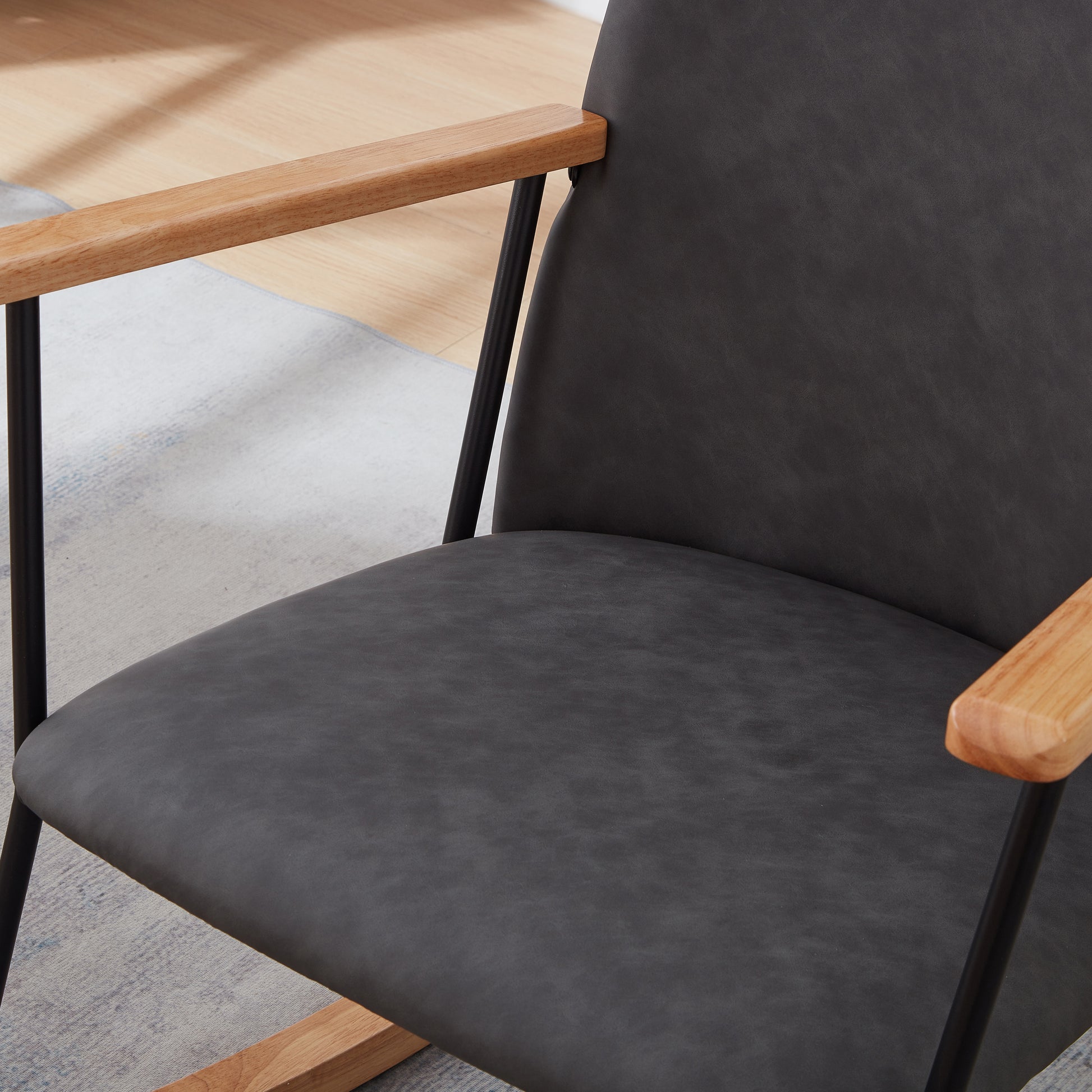 Dark gray upholstered accent chair with natural wood arms and black metal legs
