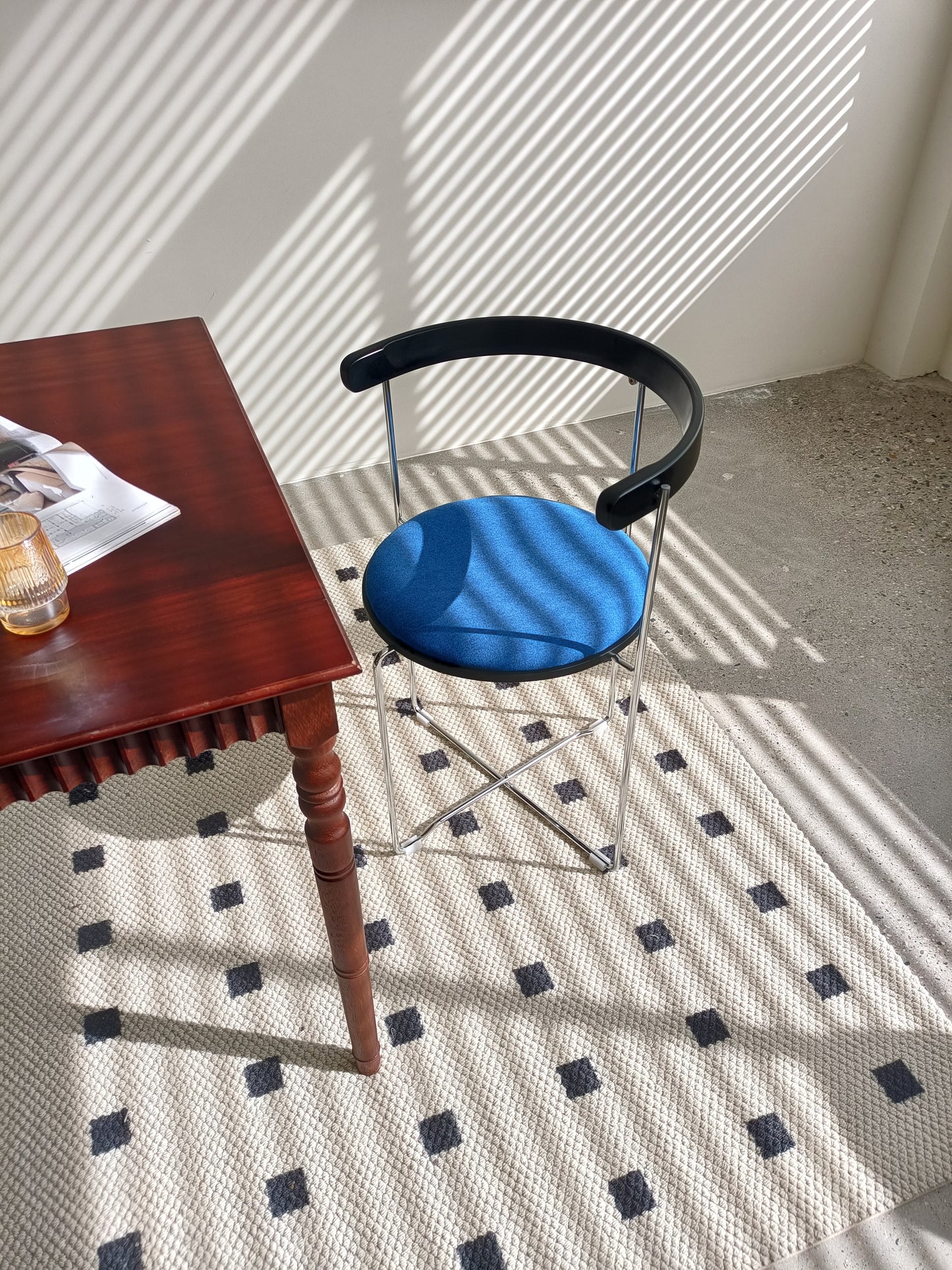 Modern blue upholstered accent chair with black curved back and chrome legs
