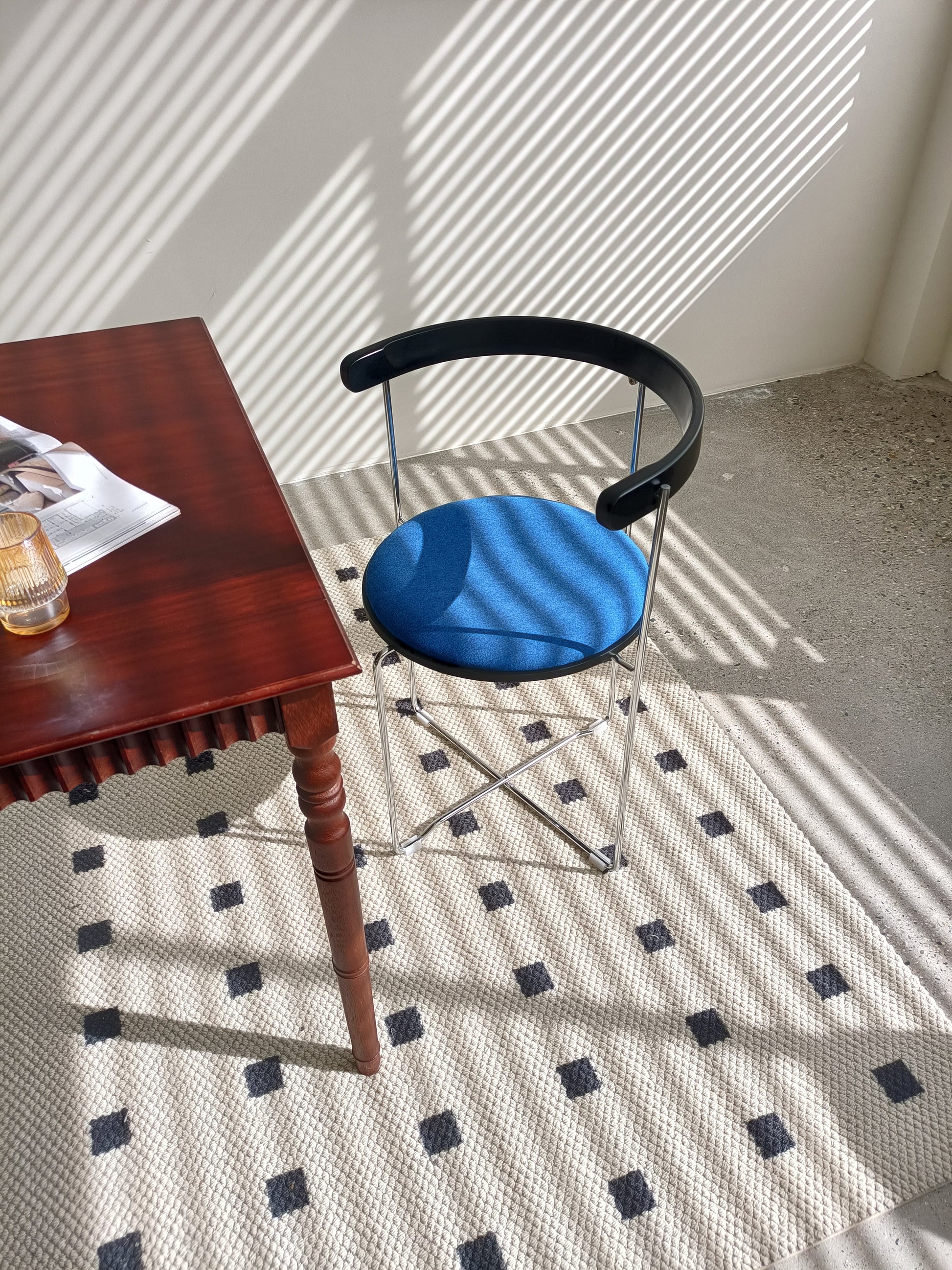 Modern blue upholstered accent chair with black curved back and chrome legs