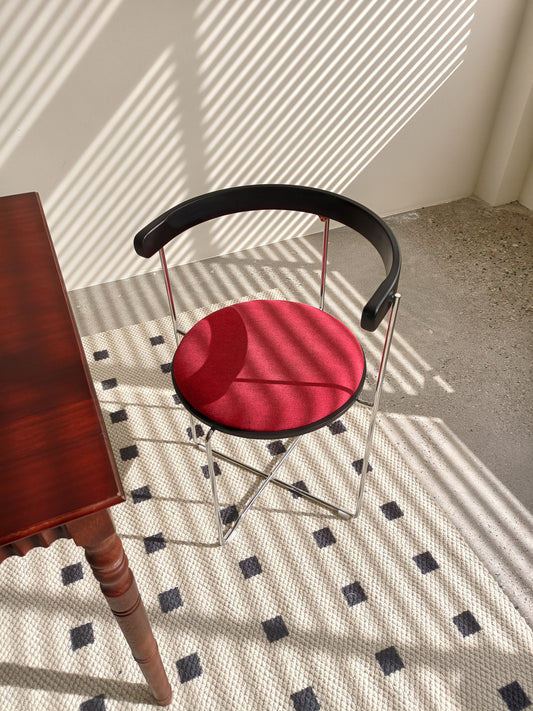Red upholstered accent chair with chrome base and black frame