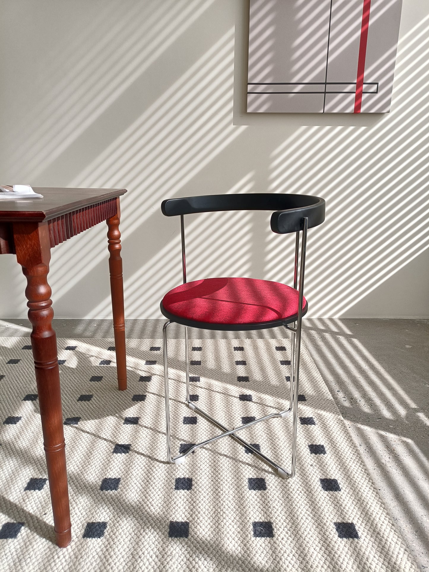 Modern black metal accent chair with a textured red upholstered seat and minimalist design