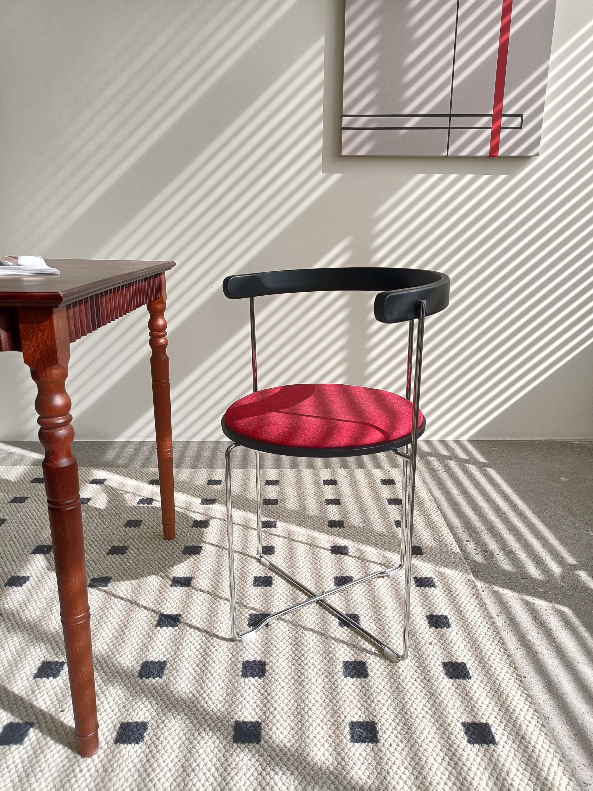 Modern black metal accent chair with a textured red upholstered seat and minimalist design