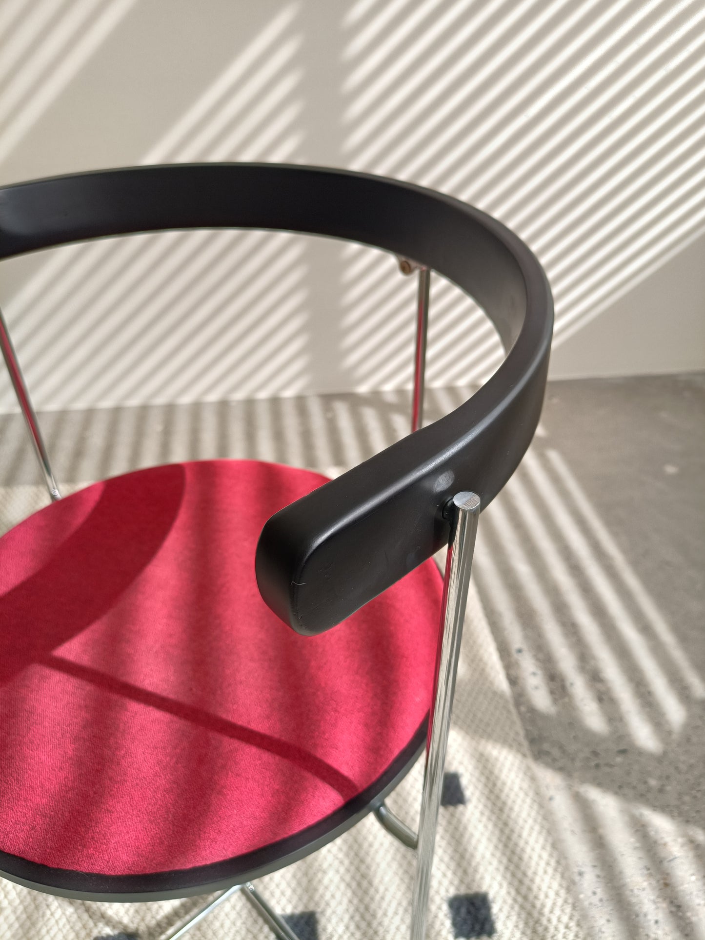 Closeup of a red upholstered chair with a black rim and chrome legs